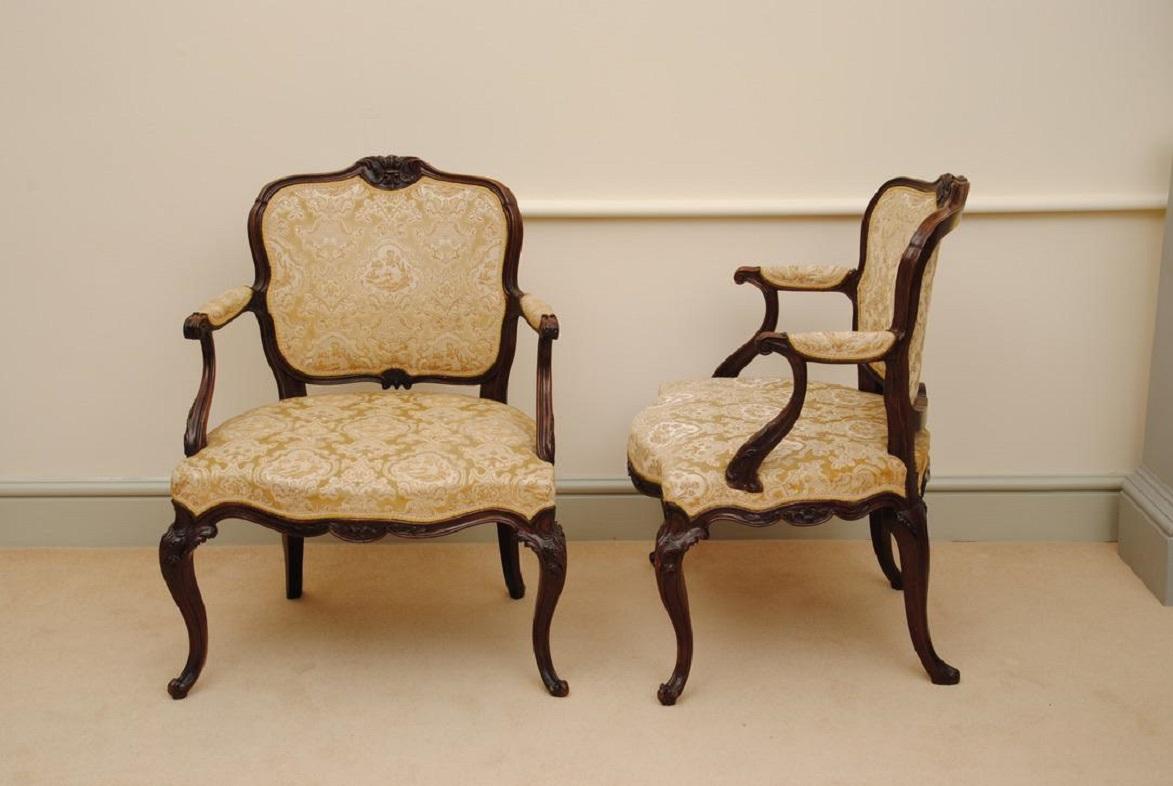 A fine pair of elegant 18th century mahogany open armchairs with intricately carved details throughout. Stood on nicely carved cabriole legs.