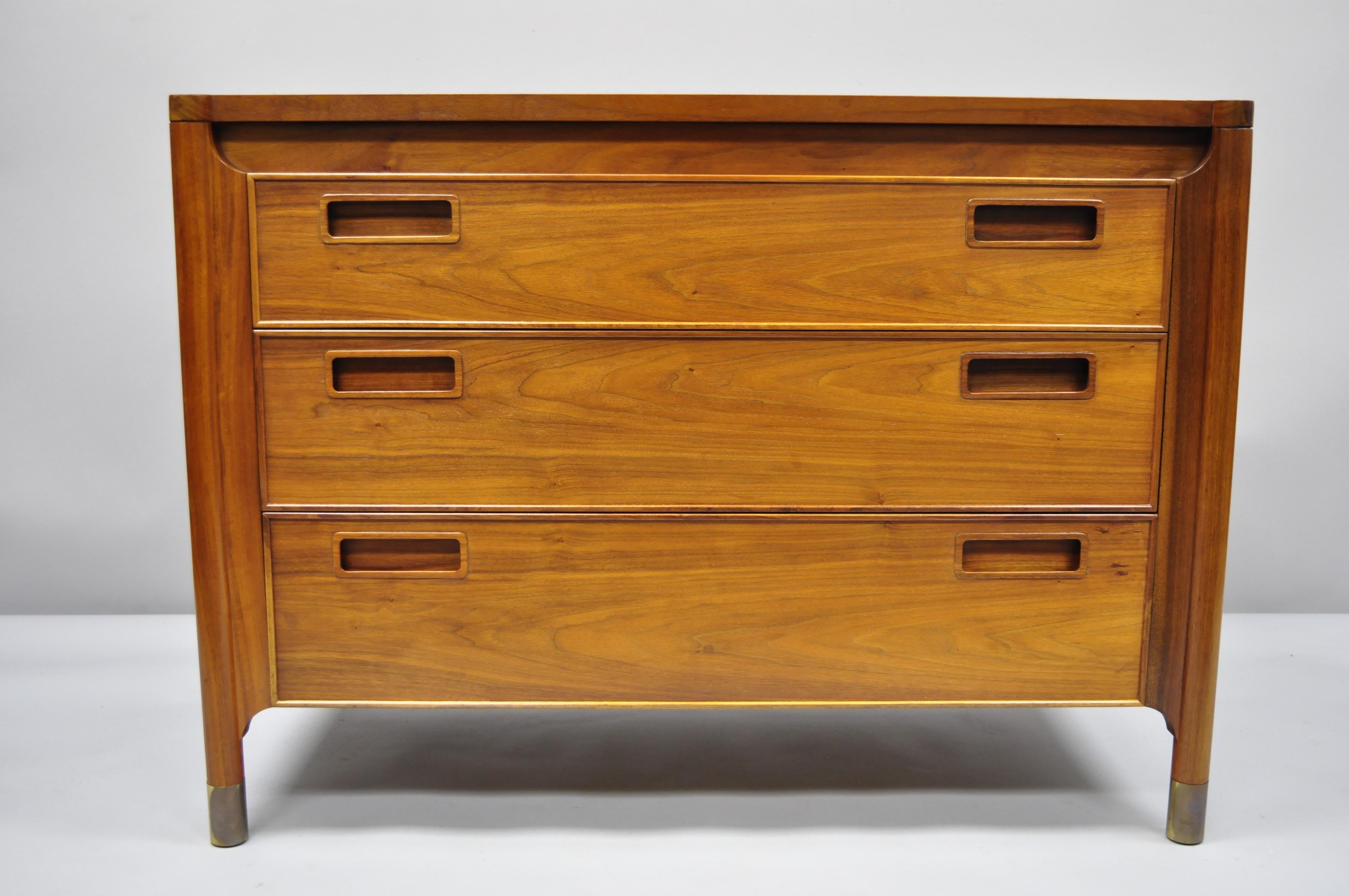 Pair of Heritage Henredon walnut 3-drawer Mid-Century Modern bachelor chest. Item features sculpted wood pulls, brass capped feet, beautiful woodgrain, finished back, original stamp, 3 dovetail drawers, clean modernist lines, quality American