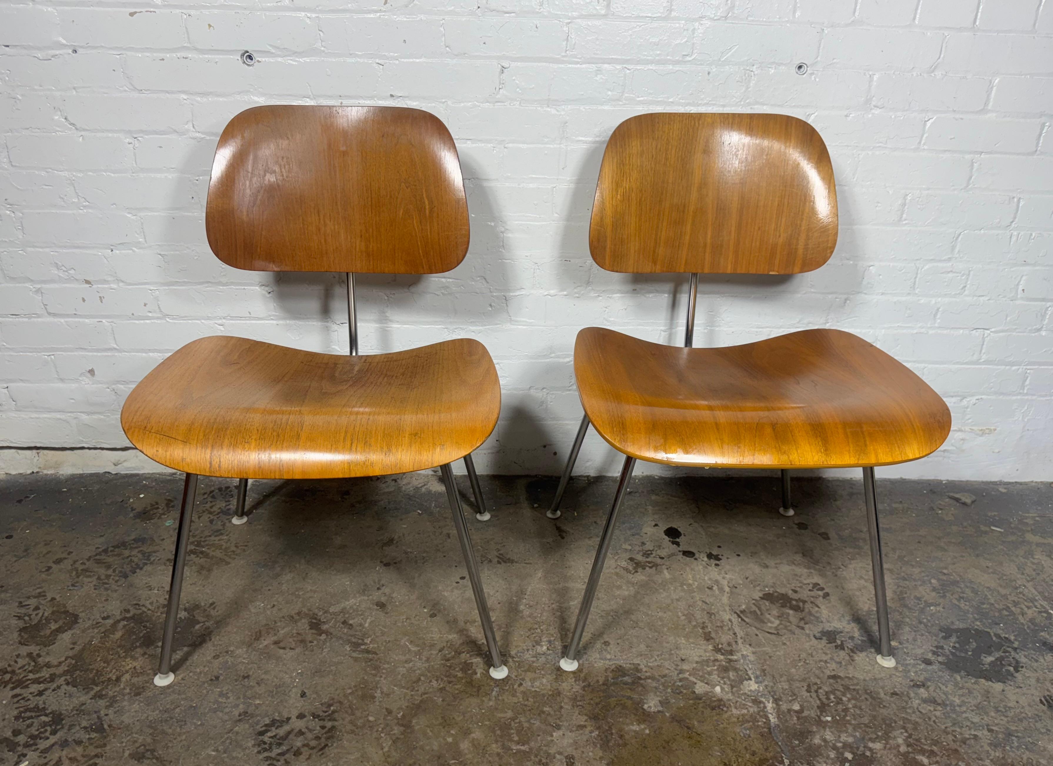 An iconic pair of Herman Miller Eames DCMs  (DINING CHAIR METAL) molded plywood side chairs c. 1980's.   Retain original (early black stripe) Herman Miller labels, These chair’s beautiful design makes them incredibly recognizable and sought after.