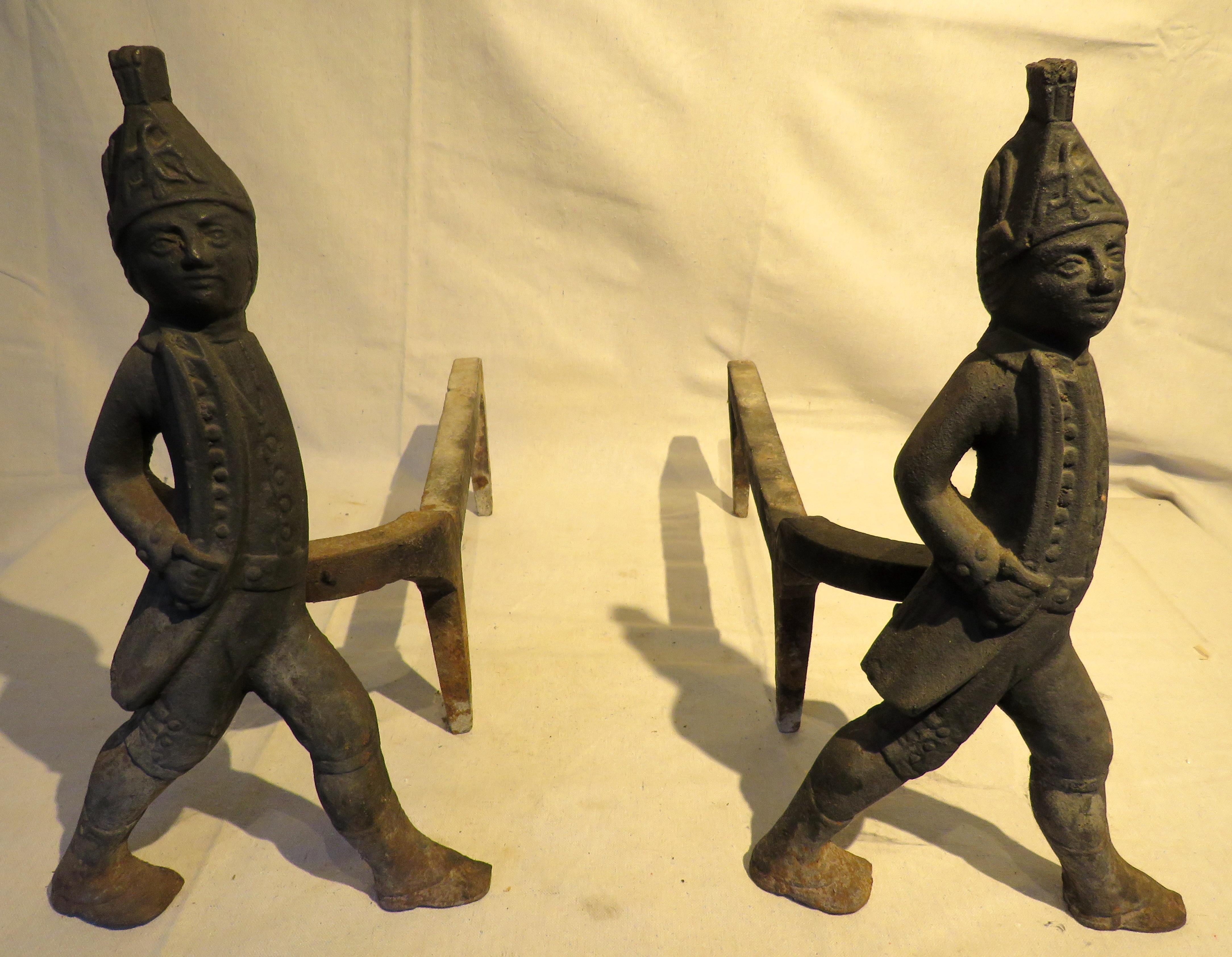 Matched pair of cast iron Hessian Fireplace Andirons. Each depicting a marching soldier in uniform, standing in semi-profile, gripping a sword. Thought to have been inspired by the strong dislike of the mercenaries brought to the country by the