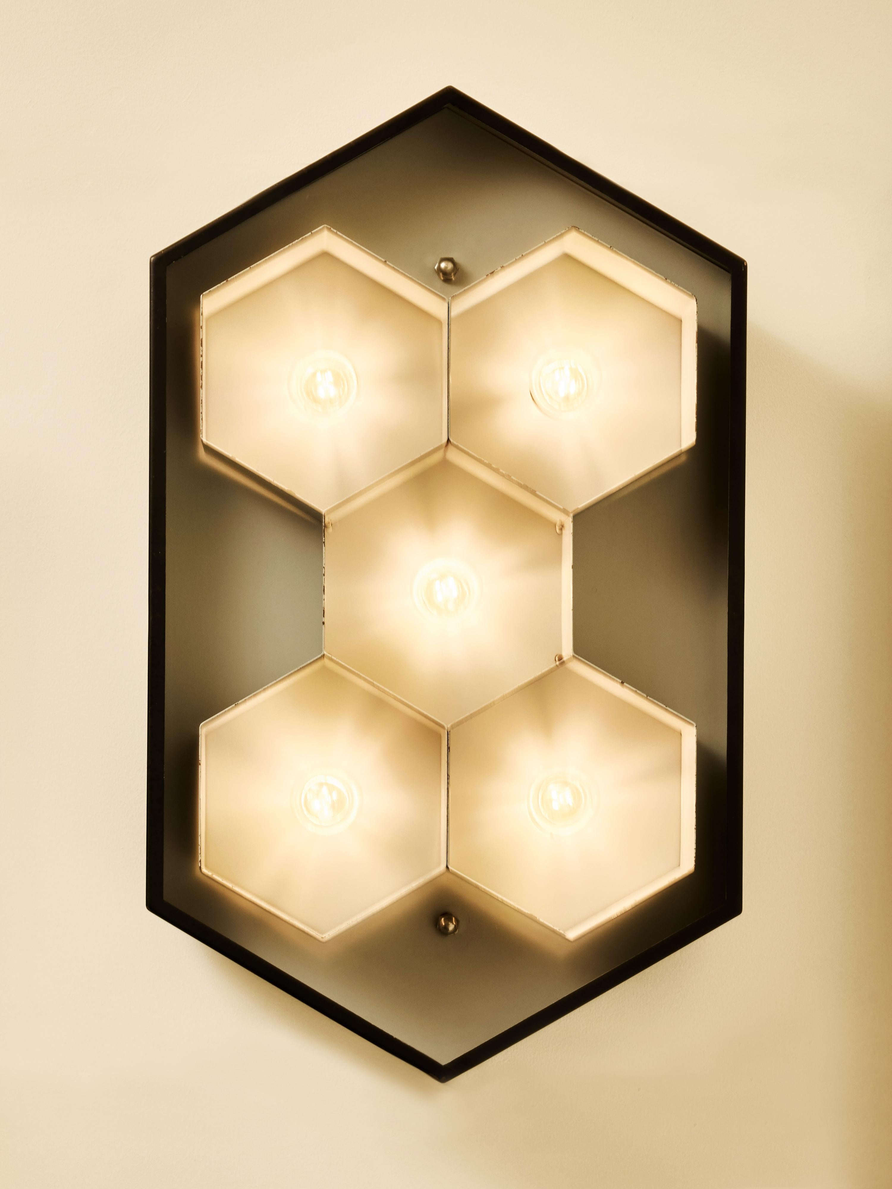 Architectural pair of 1970s French wall sconces marked Lumière, featuring a bold and sculptural hexagonal design. Each sconce presents a striking honeycomb arrangement of six hex-shaped light compartments, creating a dynamic geometric structure with