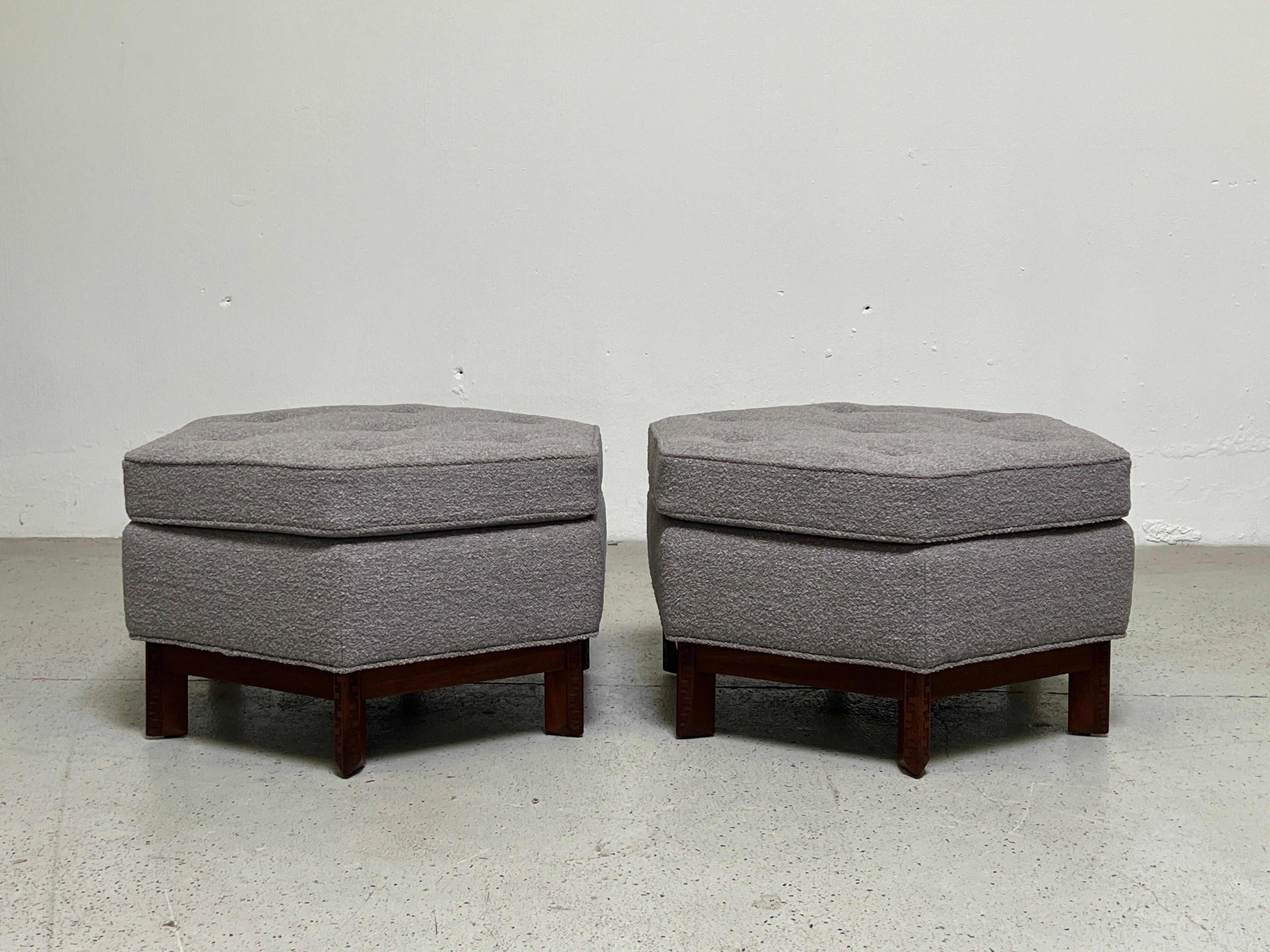 A pair of hexagonal ottomans designed by Frank Lloyd Wright for Henredon. Mahogany bases with carved Taliesin greek key details. Fully restored and upholstered in Designtex / Lambert / Smoke.