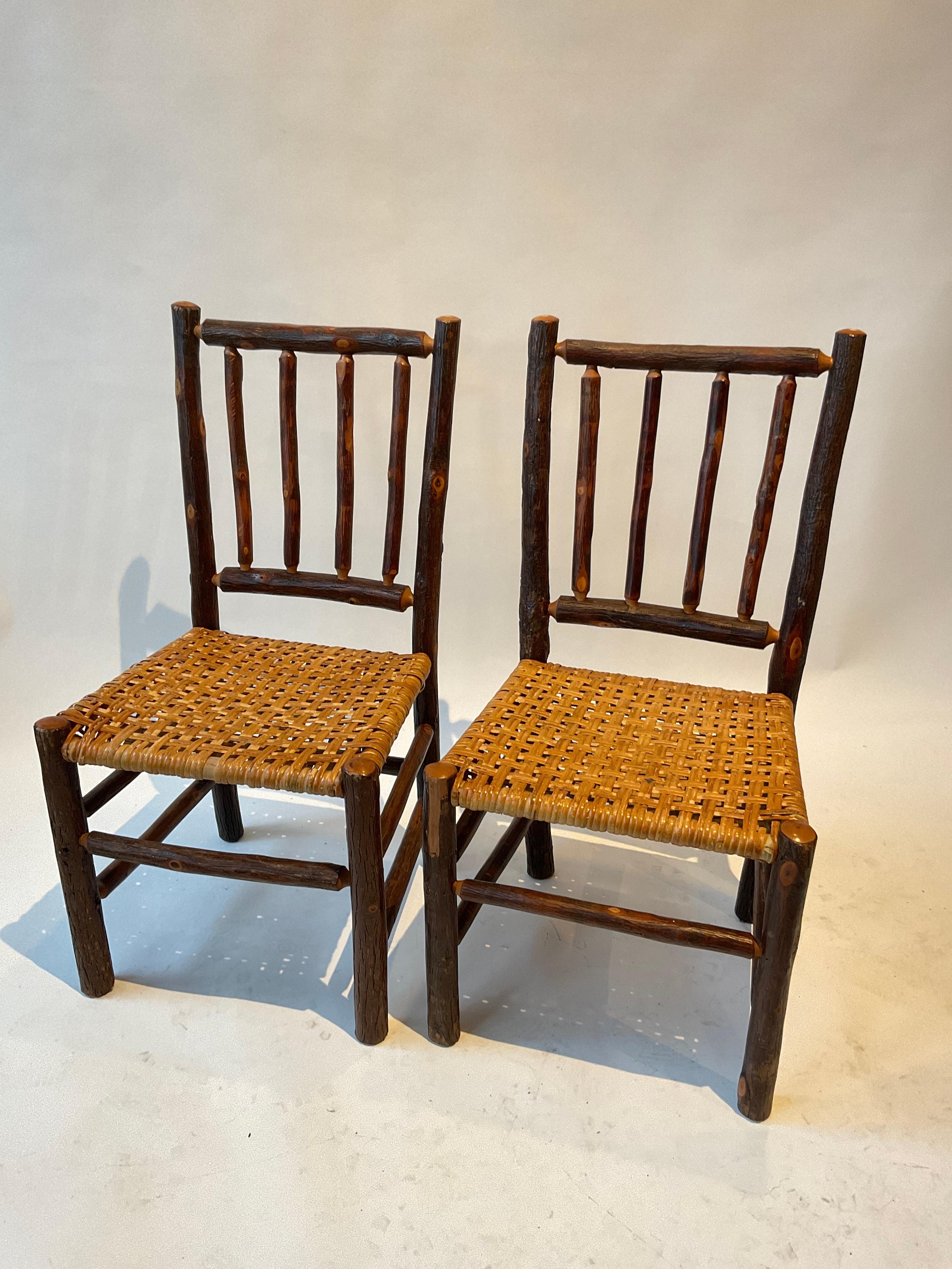 Pair of hickory wood Adirondack side chairs with wicker seats.