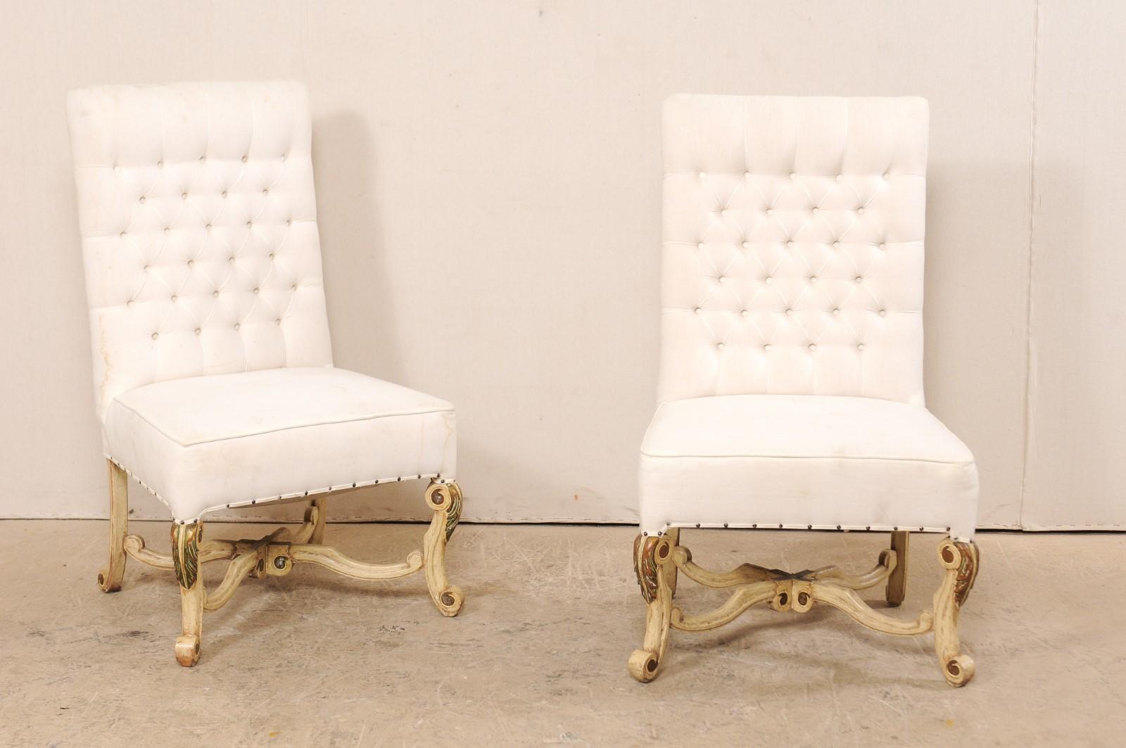 A pair of vintage American upholstered chairs with nicely carved legs and stretcher. This pair of good-sized, arm-less side chairs have an Italian inspired design, with each featuring upholstered seat and tufted backs, raised upon beautifully carved
