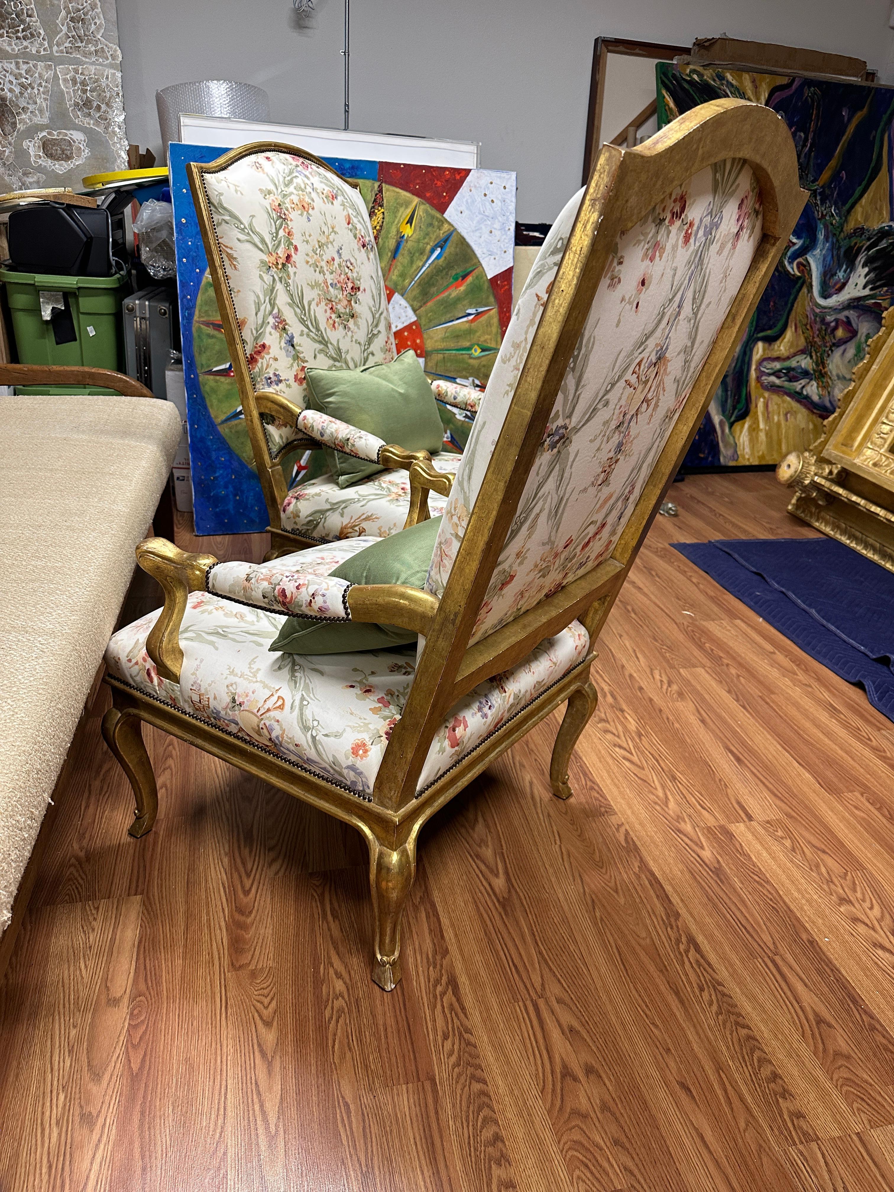 A beautiful pair of high back French Louis XV style gilt armchairs. Nicely upholstered in cotton Chintz fabric with nailhead detailing. Silk back pillows are included. We just acquired these out of a magnificent Palm Springs estate along with some