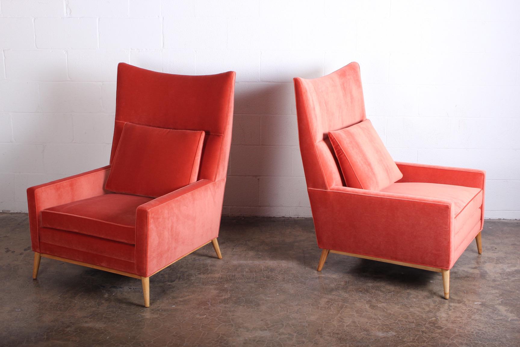 A pair of high back wing chairs designed by Paul McCobb for Winchendon. Newly upholstered in a melon colored velvet with maple legs.