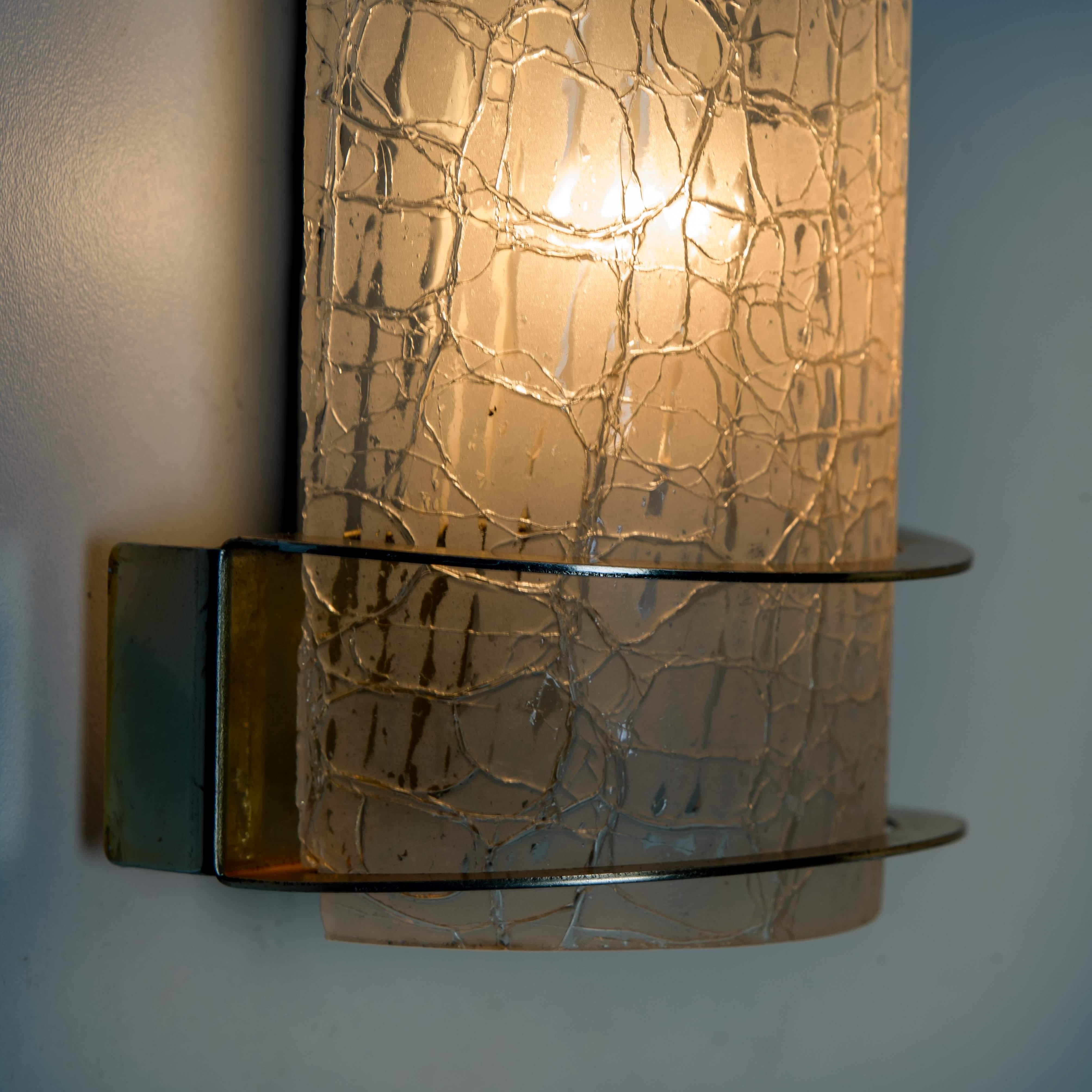 Clean lines to complement all decors. A wonderful high-end Hillebrand wall light fixture with brass detail and crackle glass. Illuminates wonderful

The wall sconce has a messing base and brass fittings with a white backplate which hold 1 E14