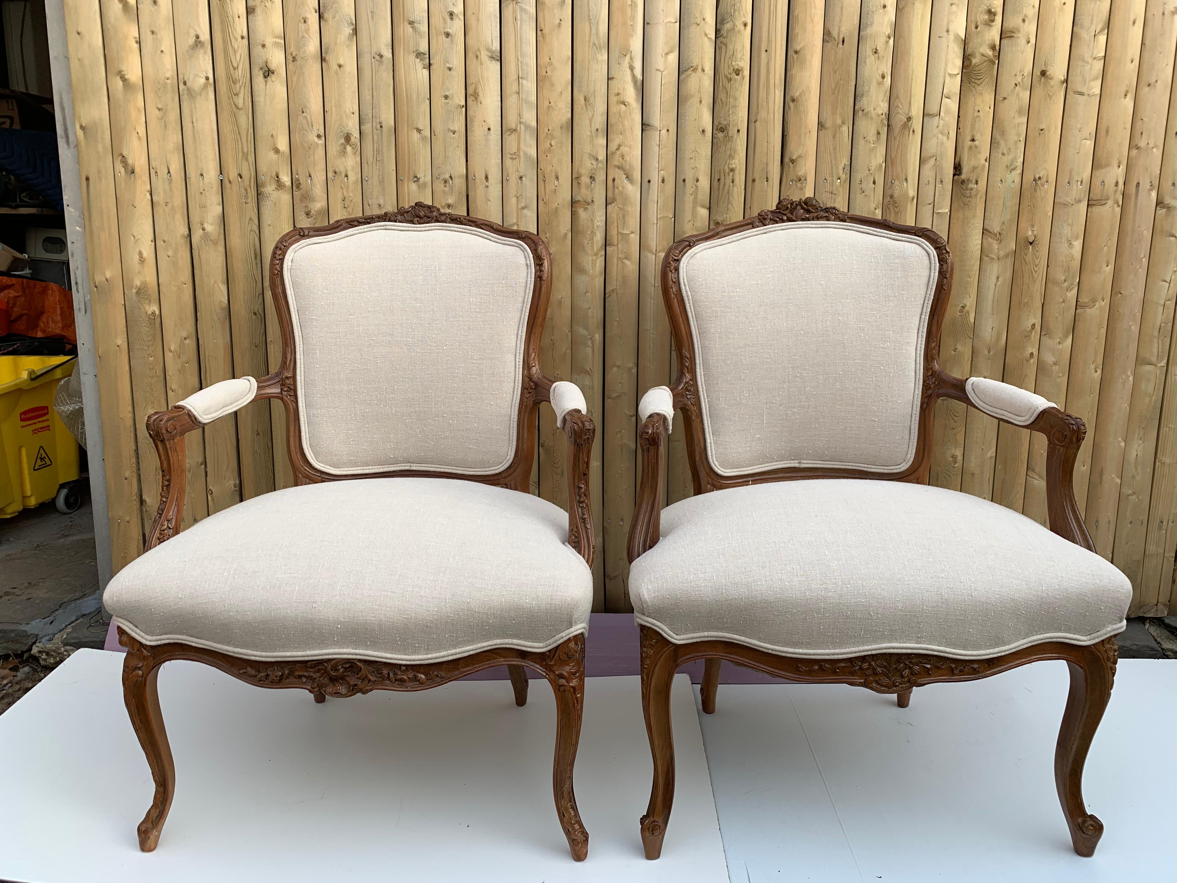 Pair of vintage carved French bergère chairs, fully refinished and newly and fully upholstered with new material and beautiful fabric, these 2 arm chairs Fauteuils  are exact same chairs in size with subtle carving differences.
