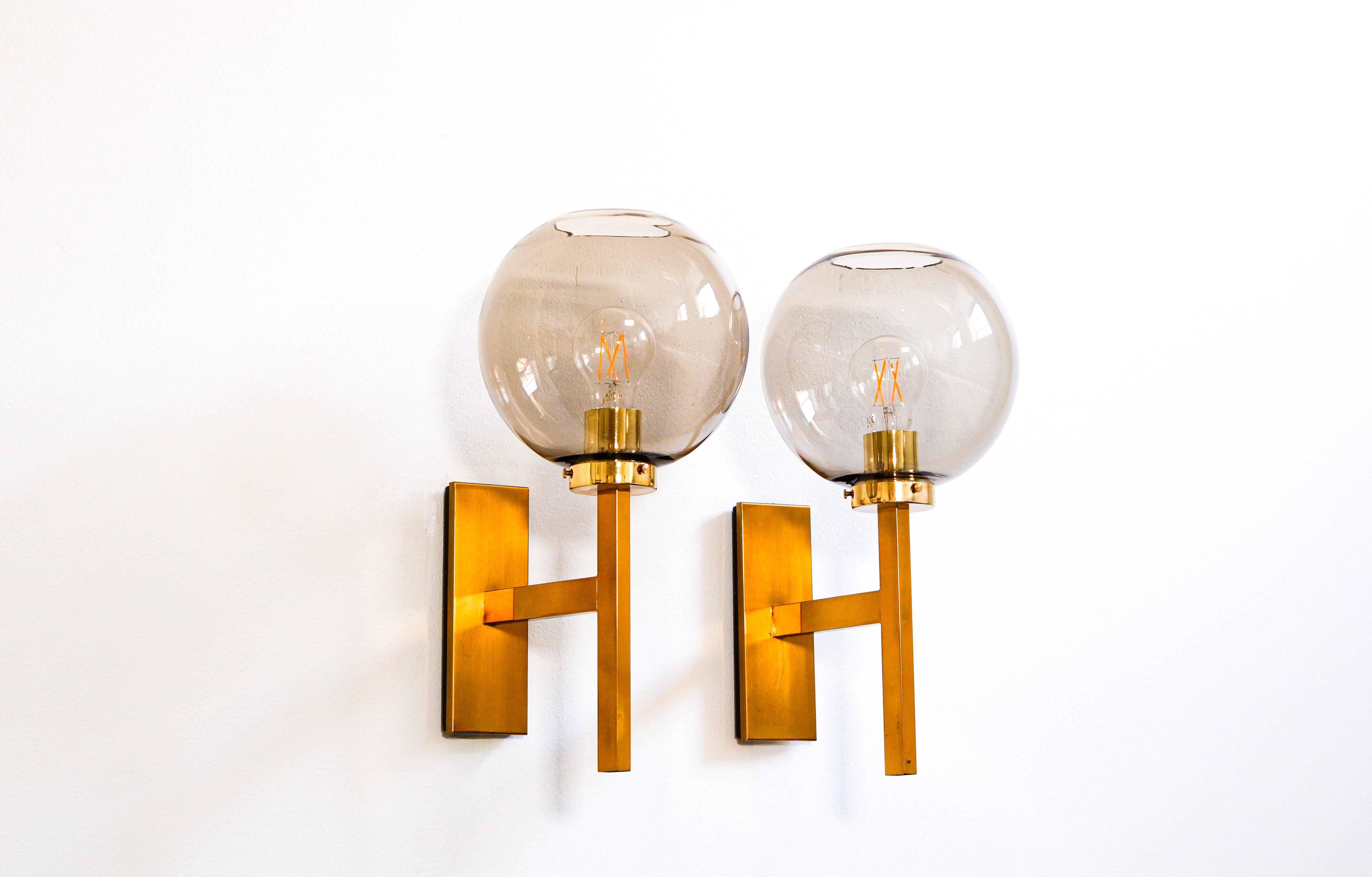 Elegant pair of Holger Johansson wall lamps deisgned and produced in the 60's by Westal. The lamp are composed with a brass core and a nice glass globe. Good overhall condition. Holger Johansson is one of the leading designer of the sczandinvian