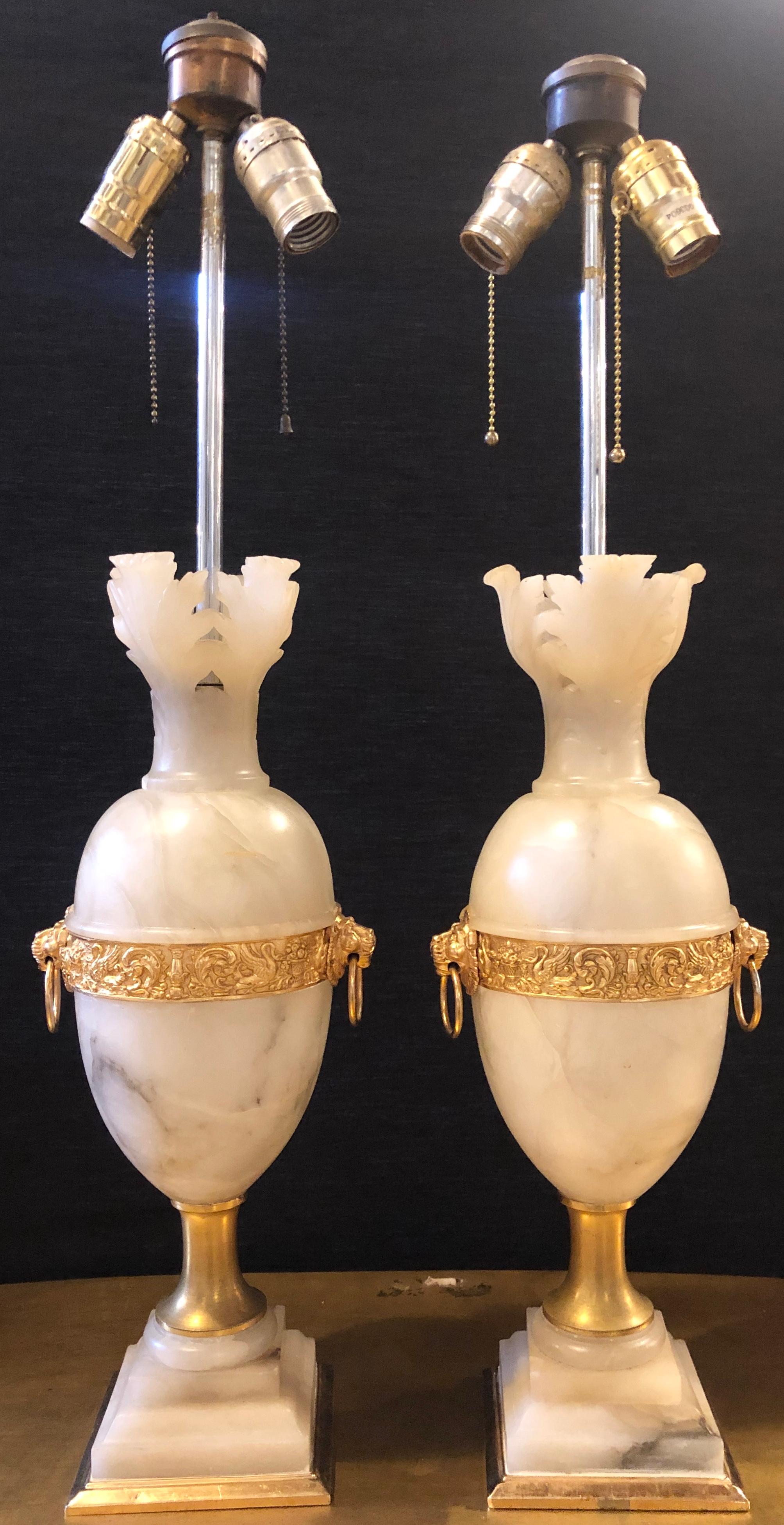 Pair of Hollywood Regency Alabaster table lamps urn form lion head. A fine pair of modern designed alabaster table lamps with gilt metal decorations. Each taking two lights without shades.