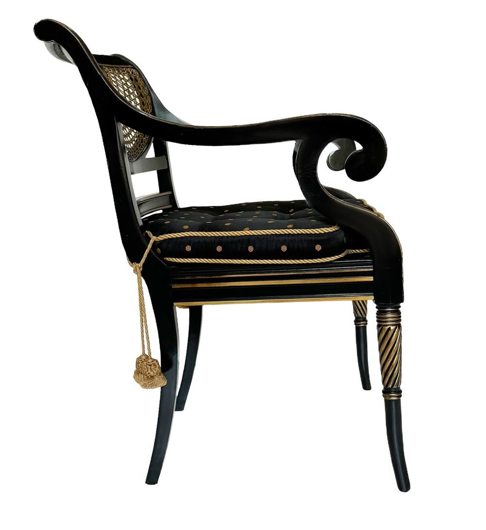 A beautifully made matching pair of Regency chairs circa 1960s. These feature solid wood construction with black paint, caning, & rope & tassel seat upholstery. Price includes pair as shown. The seat under the cushion is black caning. 