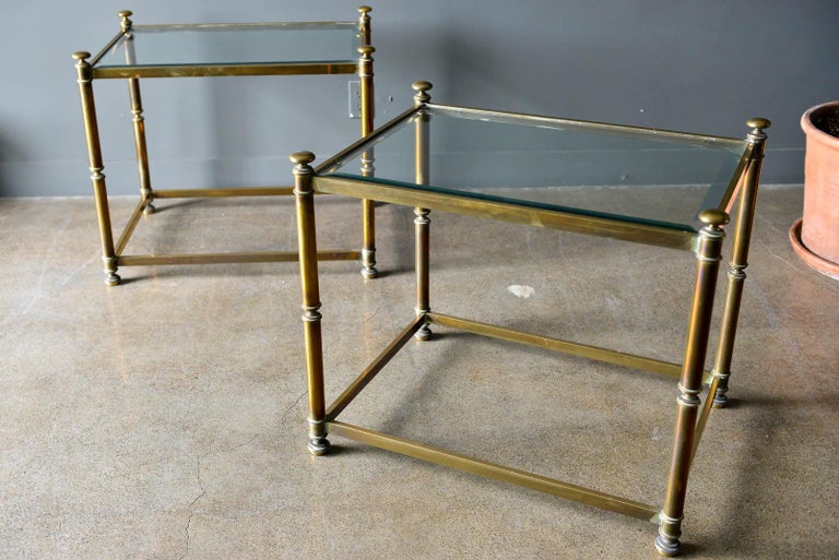 Pair of Hollywood Regency brass and beveled glass side tables, circa 1970. Glass is in excellent original condition with very light wear, no chips or cracks. Brass frames have wonderful warm patina.

Each measure 28