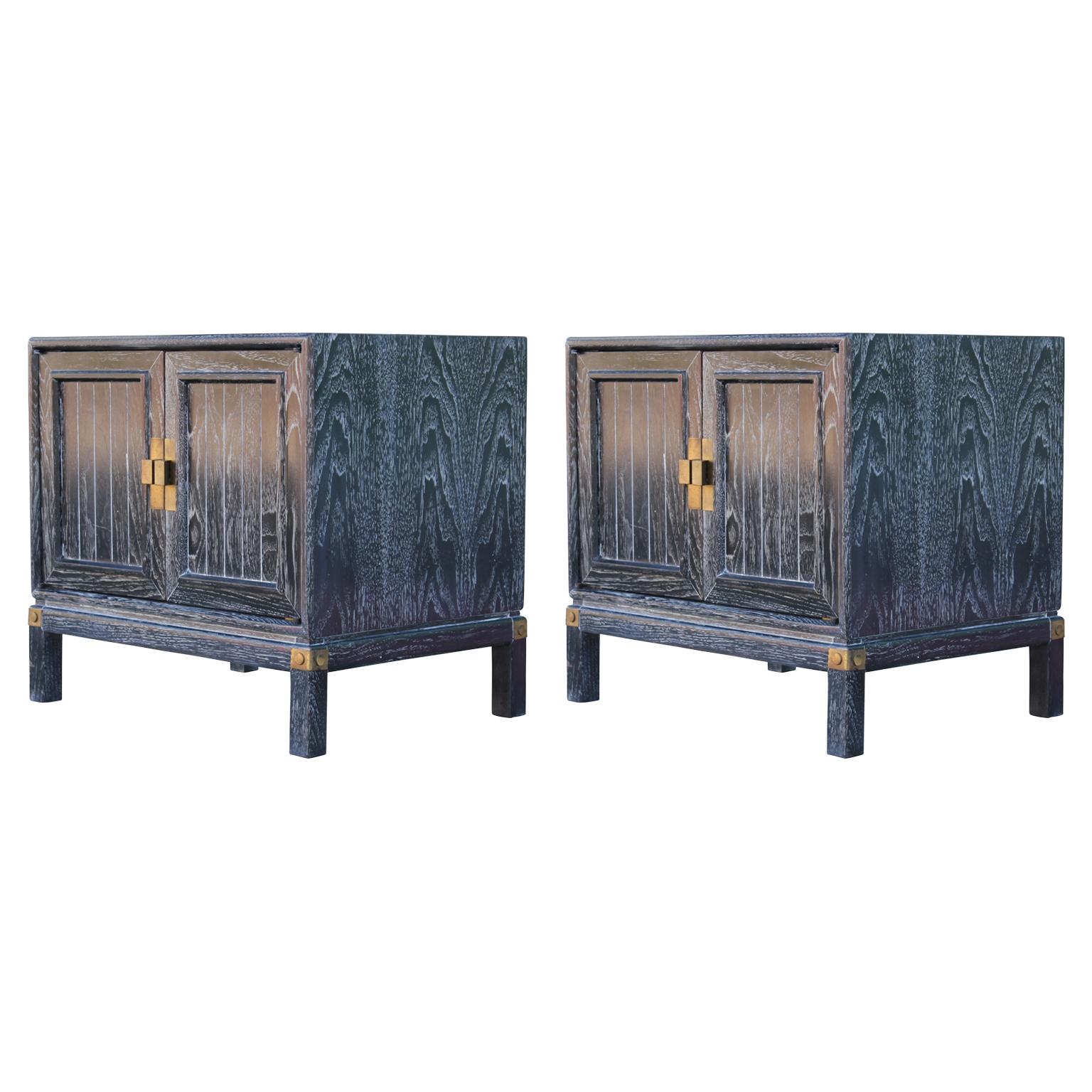 Pair of lovely Hollywood Regency style campaign nightstands that have been freshly refinished with a black and cerused finish with brass hardware. The two cabinet doors open to reveal a single shelf.