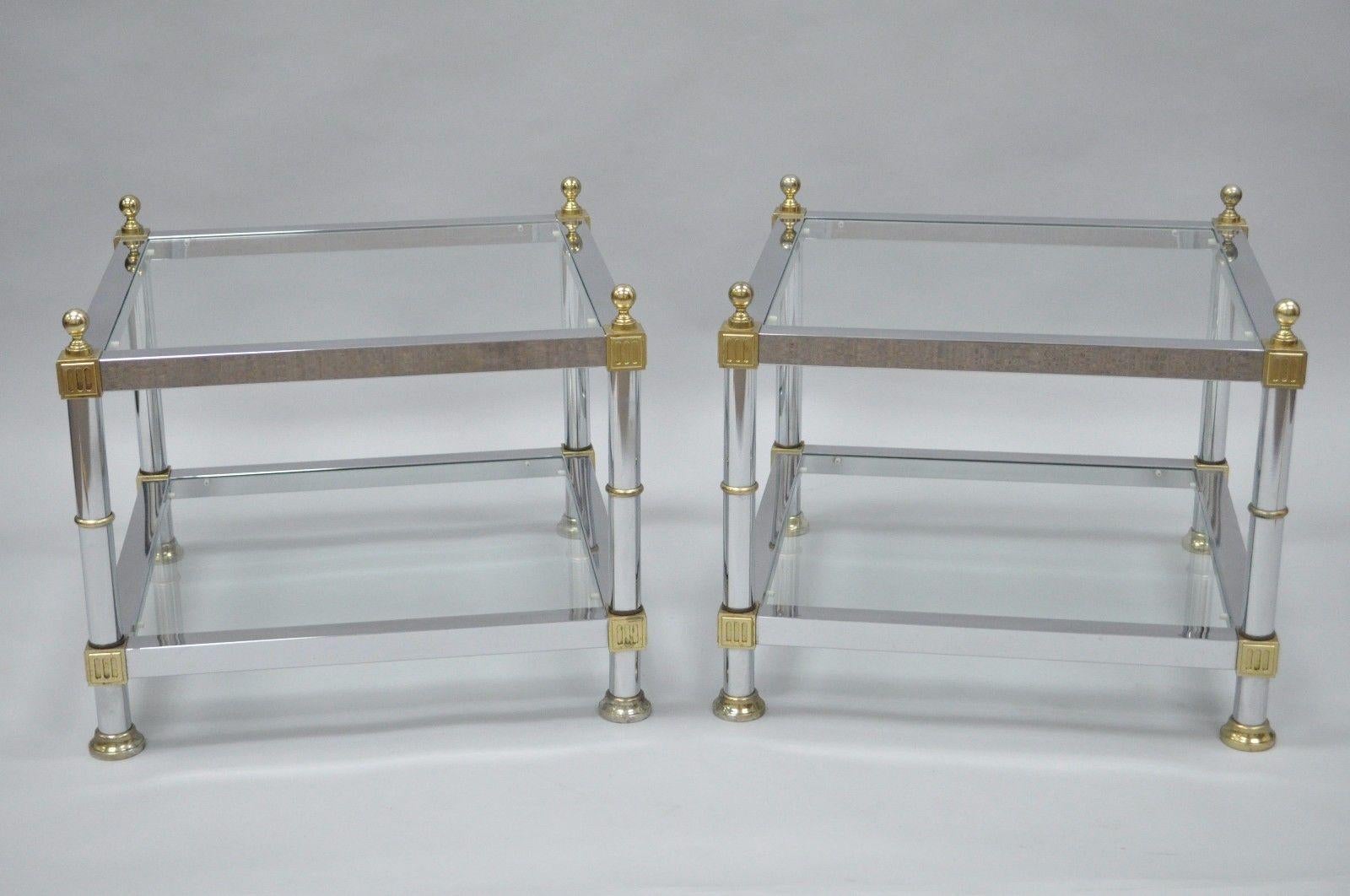 Pair of Vintage Hollywood Regency chrome, brass, and glass two-tier square side tables in the Maison Jansen style. Item features two-tier chrome metal frames, brass plated ball form finials and accents, two newly cut inset square glass surfaces,