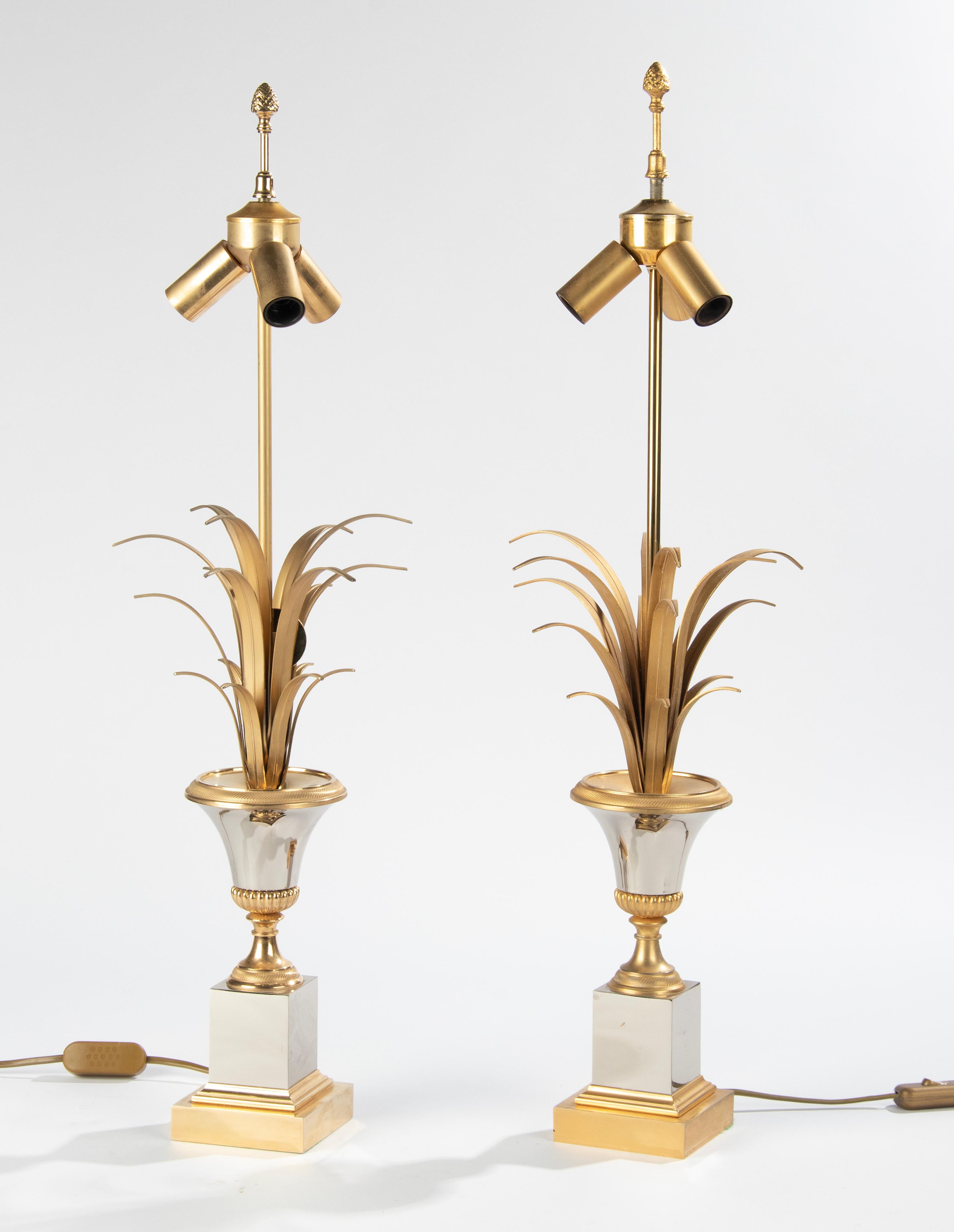 A pair of chic table lamps in the style of Maison Charles, Paris. The name of the lamp is Vase Roseaux. The lamp is made of polished chrome plated metal and casted brass. With reed or palm leaves in a vase. It has three E14 sockets. The chrome and