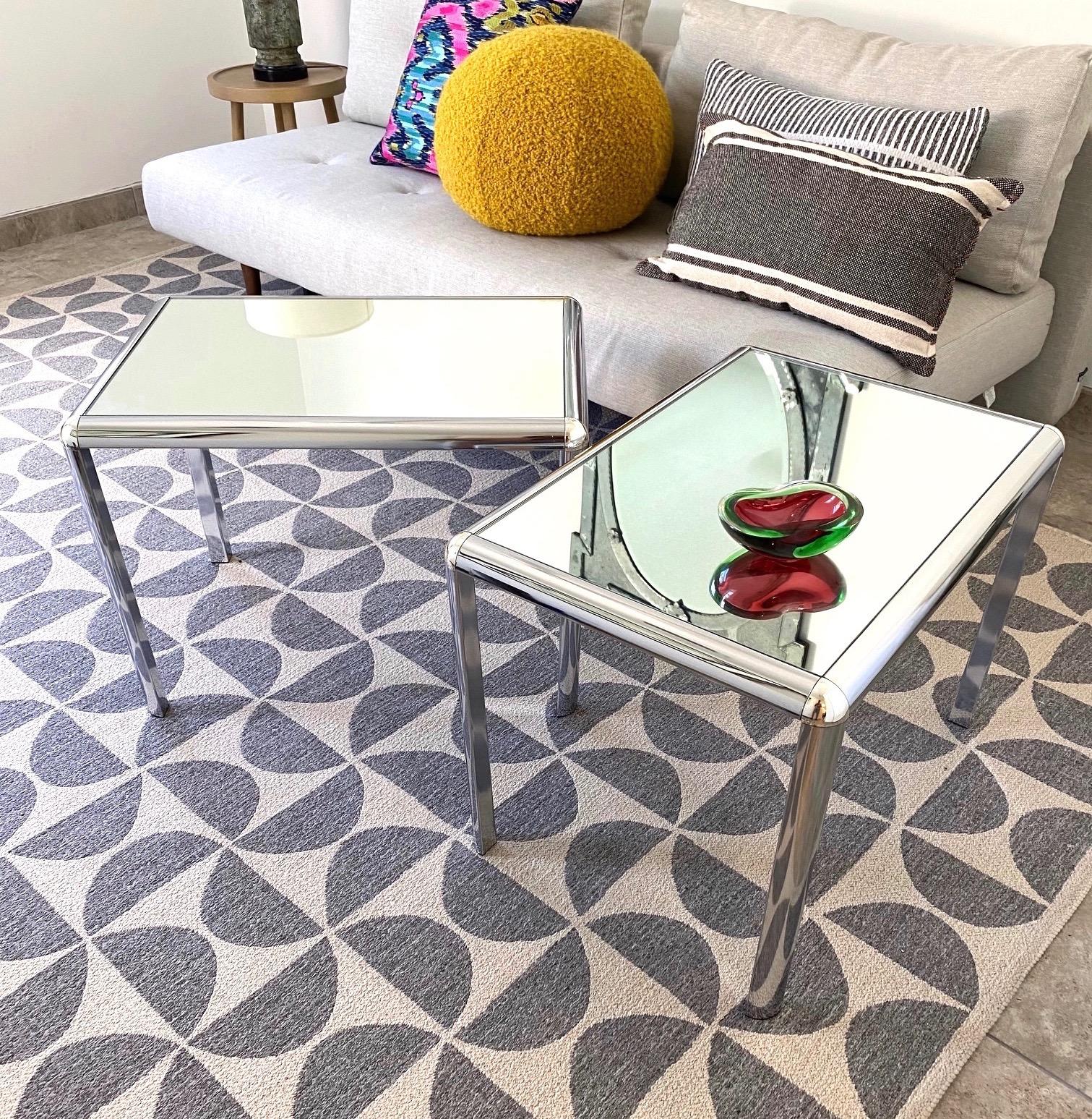 Pair of Mid-Century Modern side tables with chic minimalist frames in polished chrome. The vintage tables have a rectangular form with rounded corners and have three sided legs also with rounded fronts. The reflective frames are fitted with mirrored