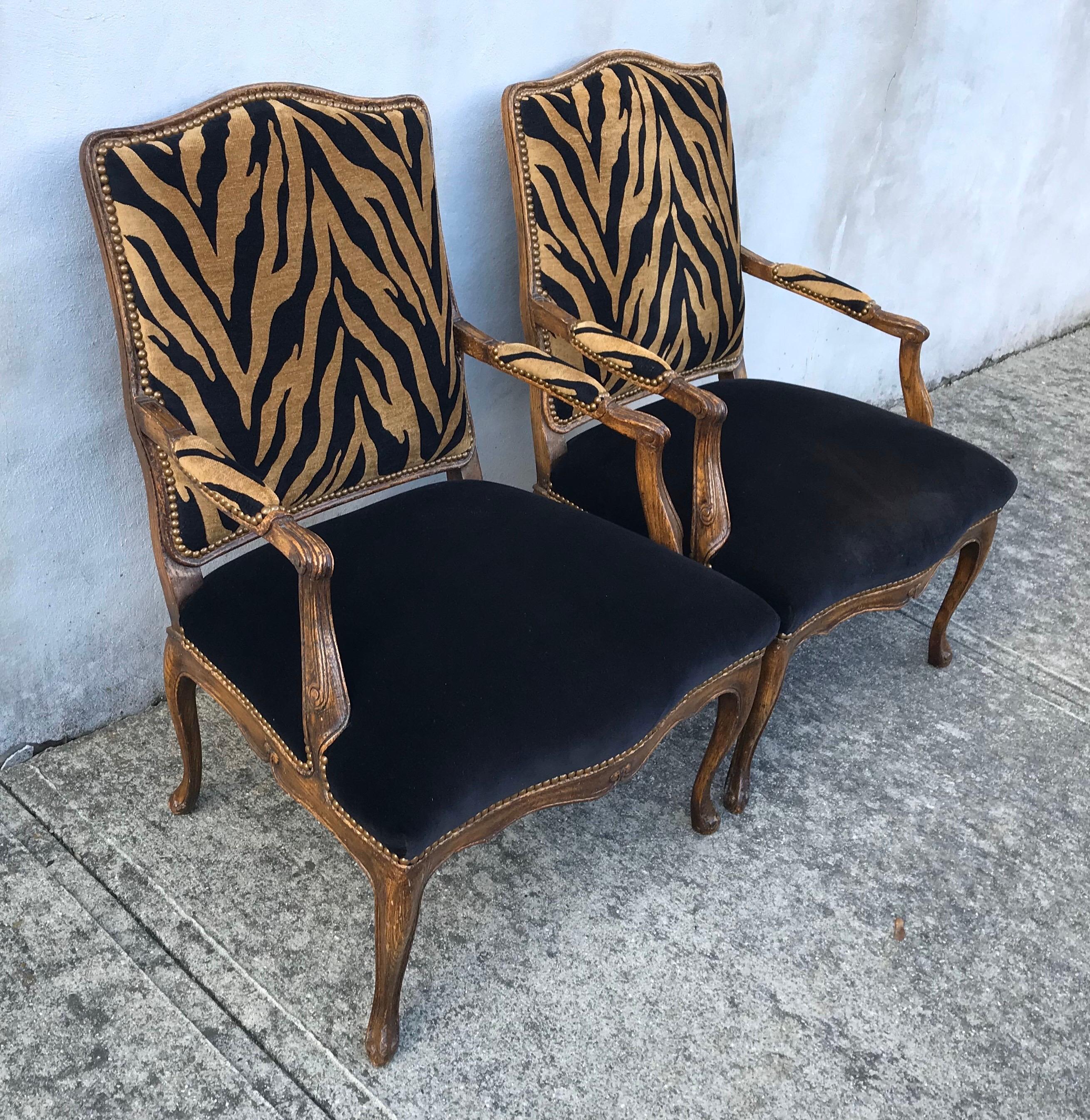 Beautiful pair of updated Hollywood Regency oak frame club chairs, recently reupholstered in zebra print velvet, black velvet seats. Oak frames date back to early 20th century.
