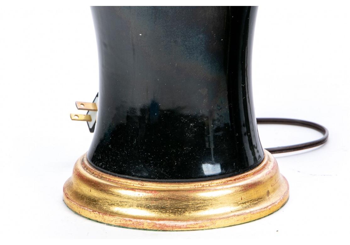 Tall black glazed ceramic vases with brass mounts as three light lamps with a white glass interior shade. Mounted on carved and gilt bases. Fine quality hardware. 
Measures: H. 31