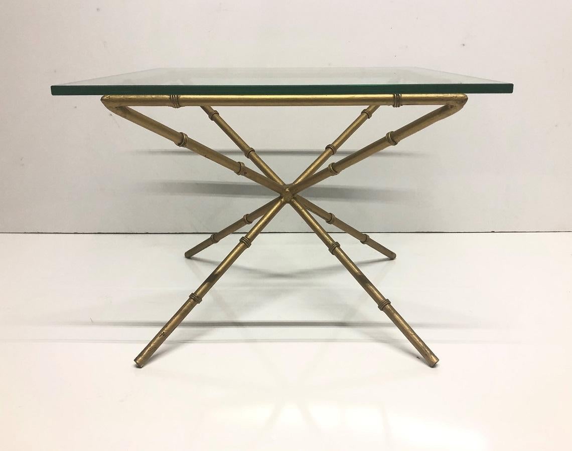 Pair of Hollywood Regency faux bamboo glass top side tables. The tables have gold metal bases with a faux bamboo pattern.