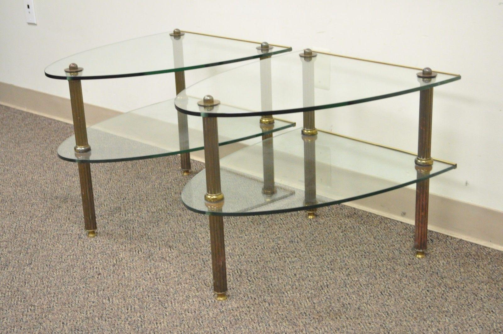 Pair of vintage Hollywood Regency French style brass and glass two-tier side tables after Maison Jansen. Item features two shaped glass tiers, reeded column brass legs, beautiful authentic patina to brass, circa 1950. Measurements: 19