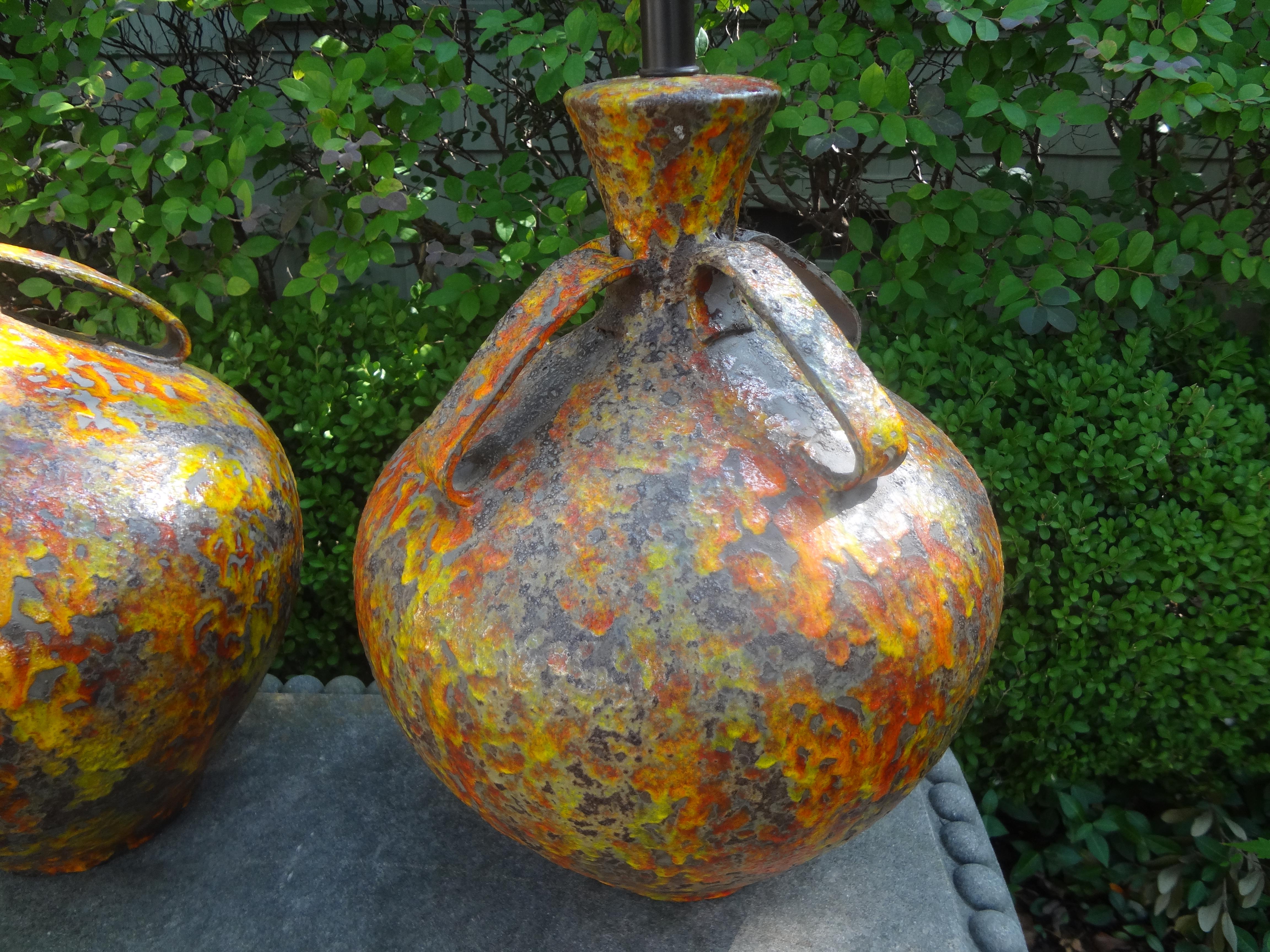 Pair of Hollywood regency glazed ceramic lamps. This stunning pair of midcentury lamps were executed in beautiful tones of oranges, yellows and browns with four handles on each. These chic lamps have been newly wired with new sockets for the