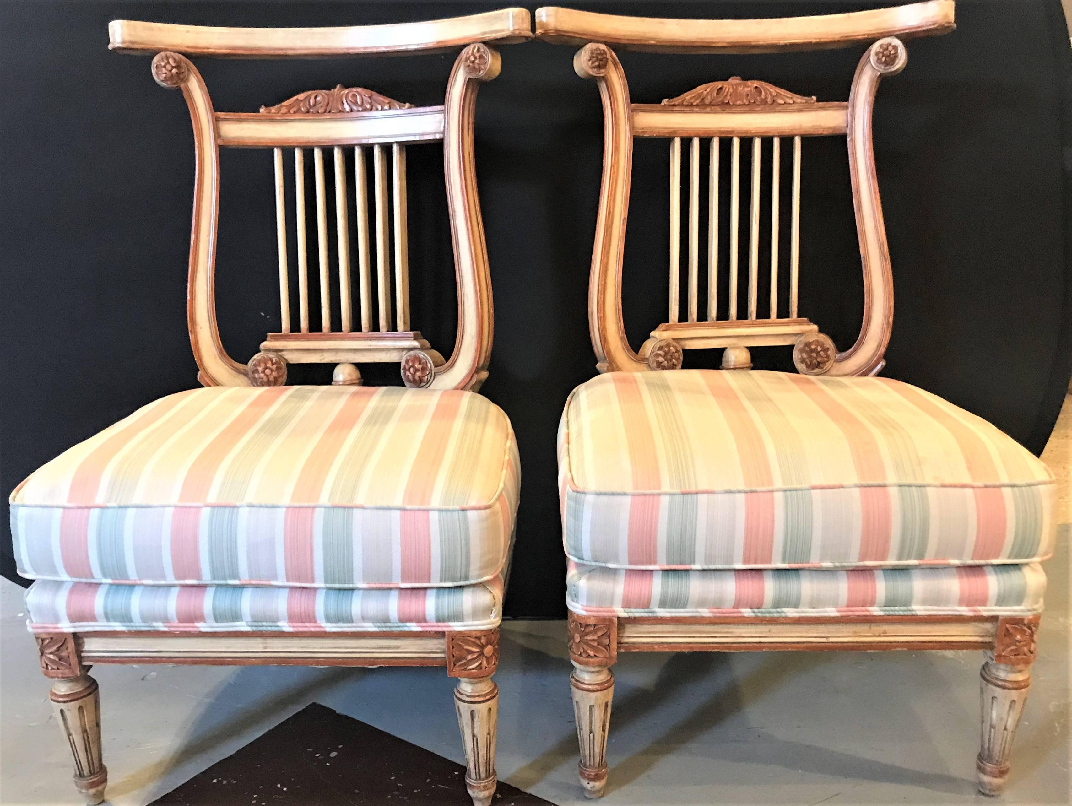 A pair of Hollywood Regency low French lyre back side or slipper chairs in manner of Jansen. Each in the Louis XVI style having lyre backs with painted and clay decorated frames. Both in a stripped fabric.