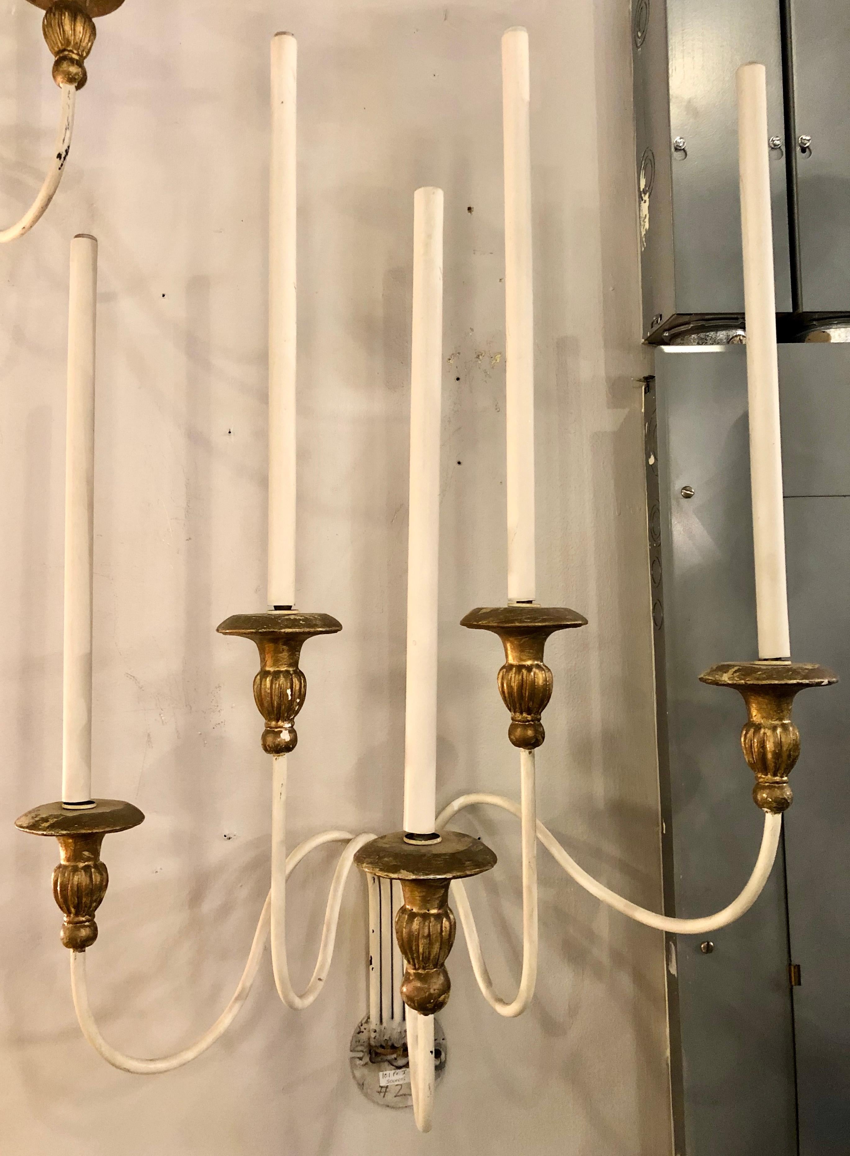 Pair of Hollywood Regency Maison Jansen wall sconces. A large and impressive pair of paint and parcel-gilt decorated wall scones. The pair having metal frames with gilt gold bobeches and large impressive flowing arms. Distressed.