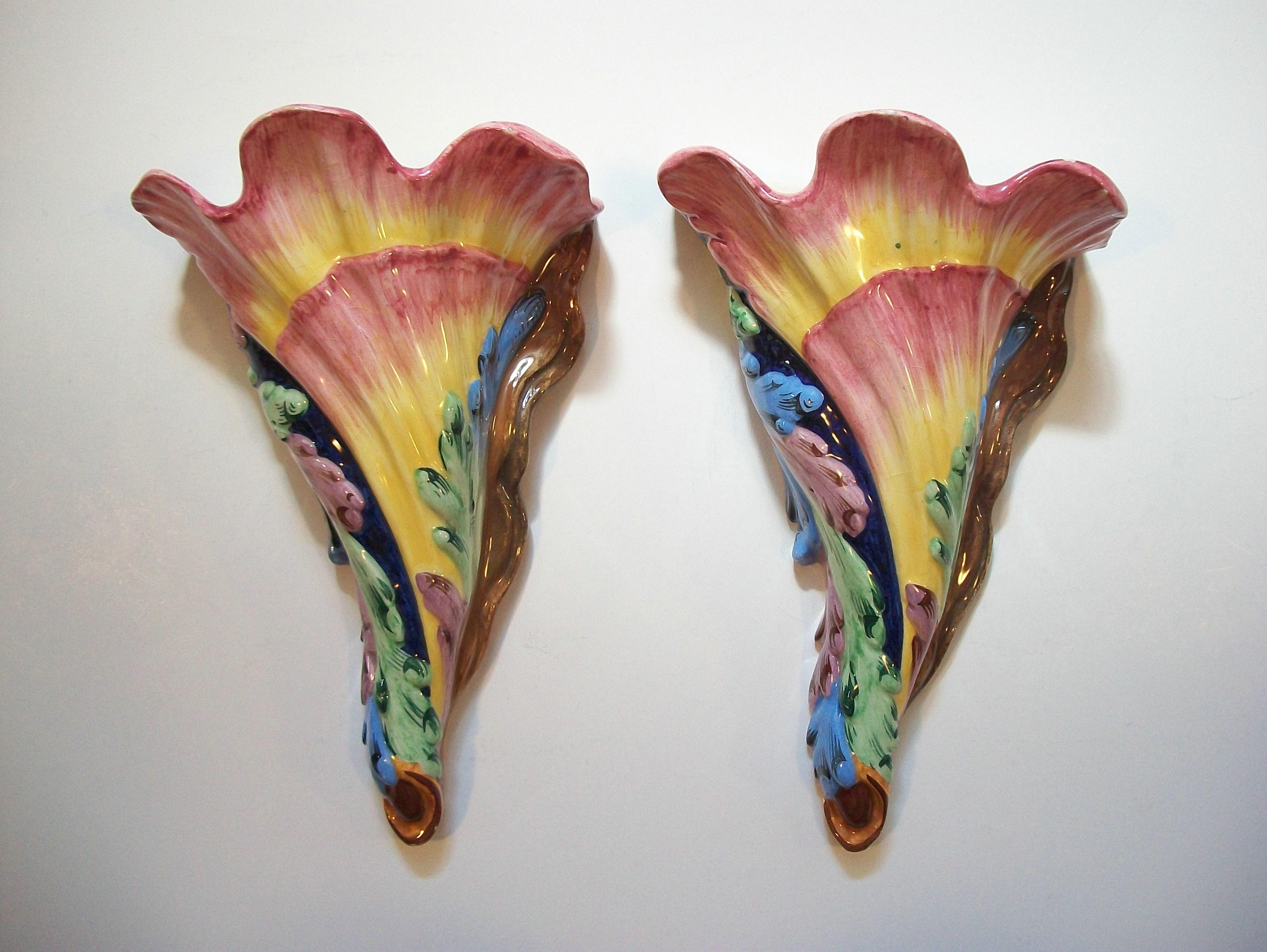 Fine pair of exuberant Hollywood Regency majolica wall pockets - featuring colorful hand painted acanthus leaves set against the trumpet shaped floral body - the glaze with a smooth glossy finish - cream glaze to the interior - the backs left