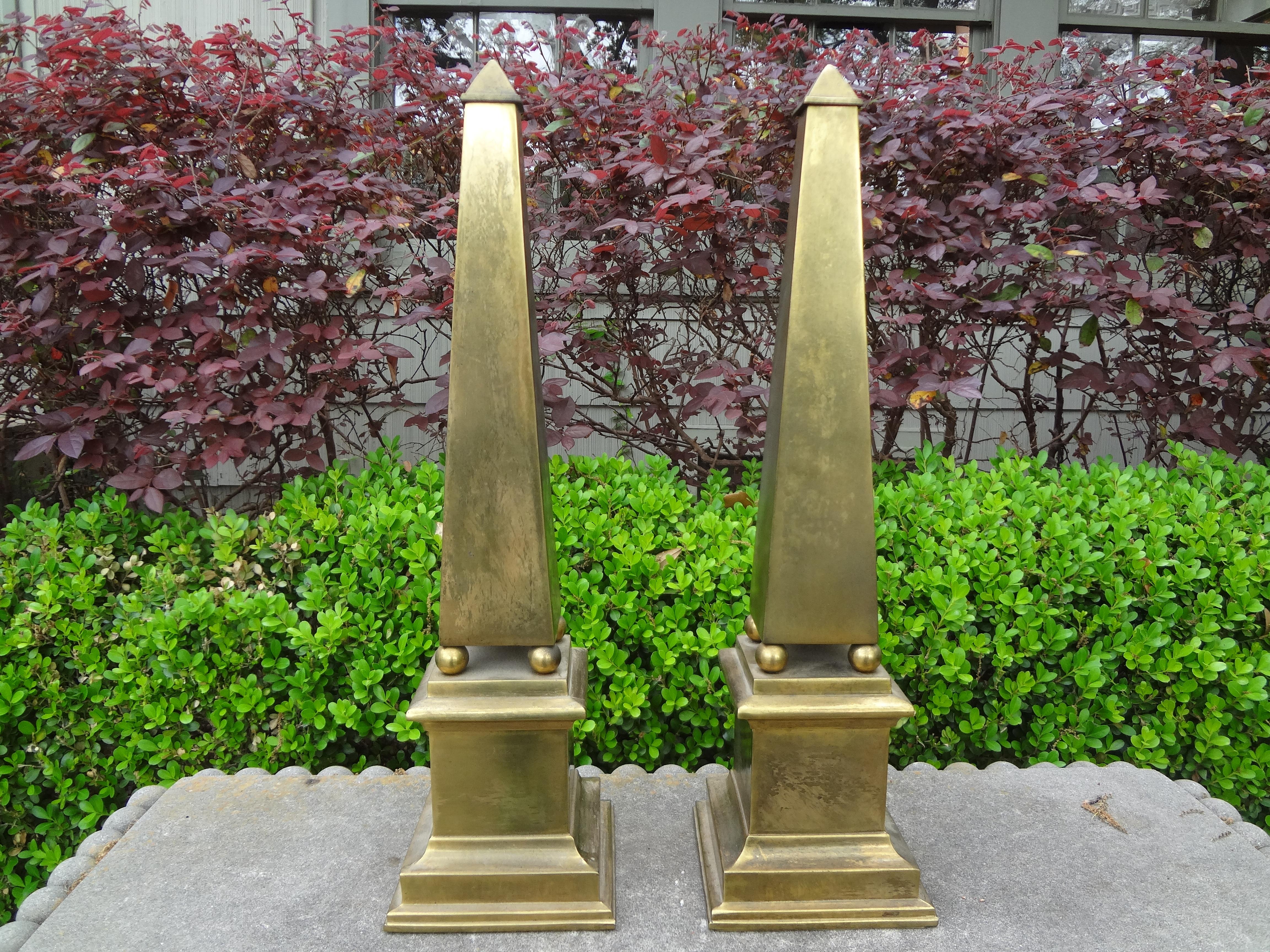 Great pair of Hollywood Regency brass obelisks. These beautiful midcentury neoclassical style brass obelisks have a naturally occurring patina that could be polished if desired. Perfect table or bookcase accessory!