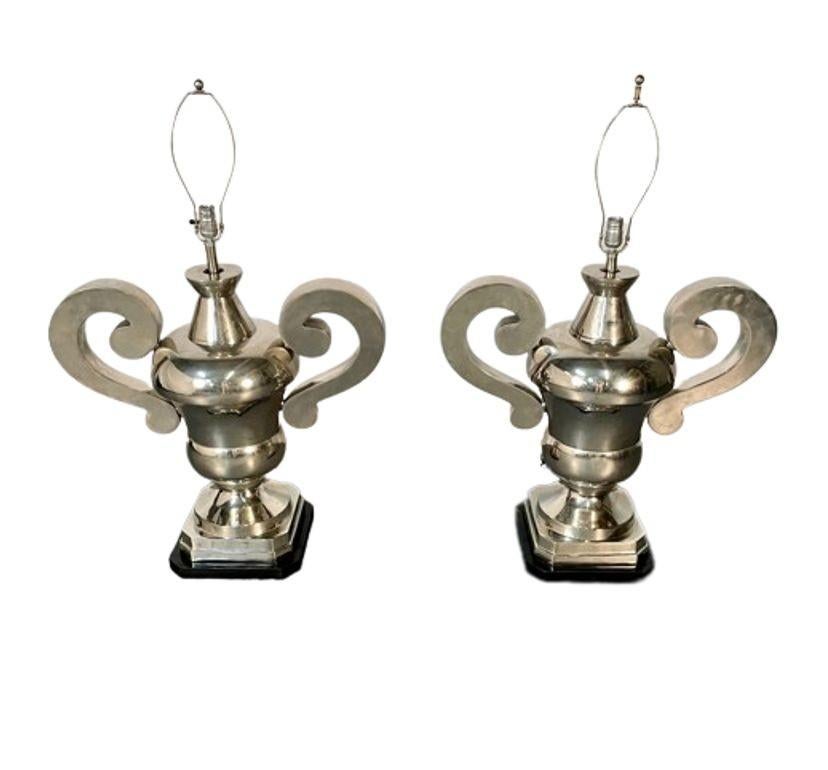 A Pair of Polished Nickel Plated Impressive Urn Form Table Lamps resting on black marble bases, American C. 1980's
 
Large and Impressive in size these sleek and stylish table lamps are sure to inspire. 54 Inches High to top lamp shade. Lamp Shades