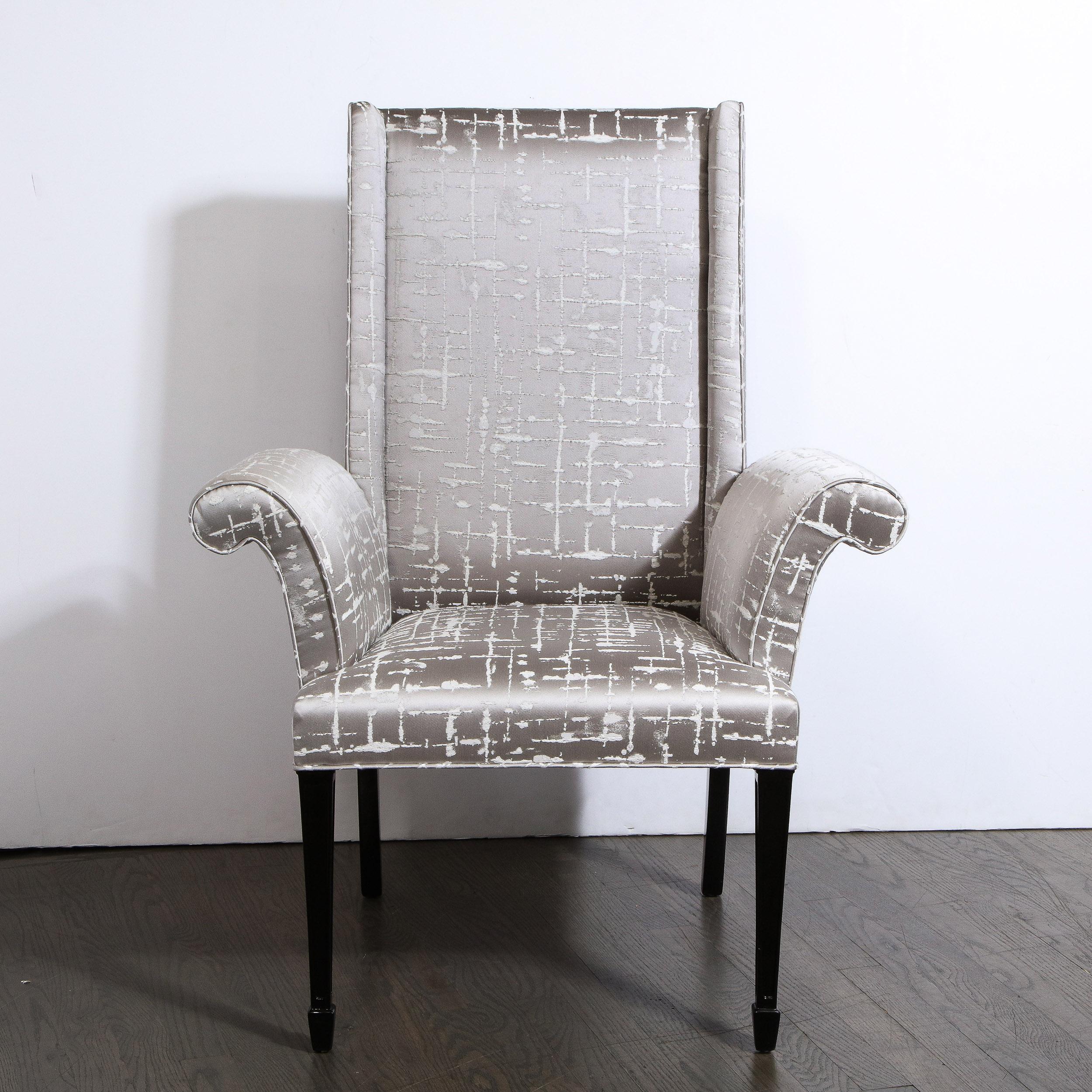Cette élégante paire de fauteuils Hollywood Regency a été réalisée aux États-Unis, vers 1940. Ils sont dotés de pieds rectangulaires volumétriques stylisés de style klismos en noyer ébonisé. Les pieds avant présentent un détail géométrique effilé à