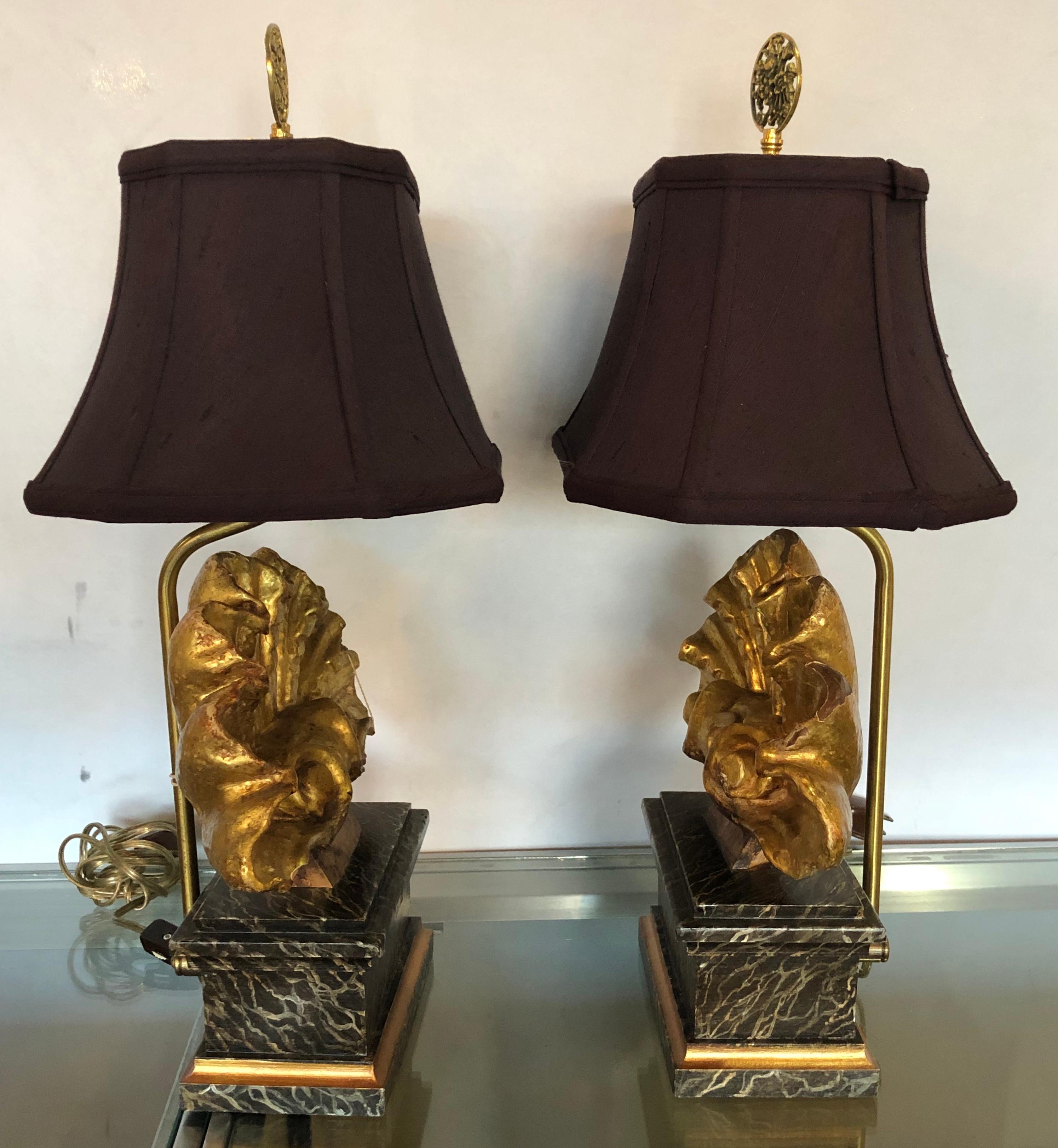 Pair of Italian shell carved gilt and faux marble decorated table lamps in the Hollywood Regency fashion. Each having a custom quality shade with gilt metal finals. The carved giltwood shell centres on faux marble bases are simply stunning and are