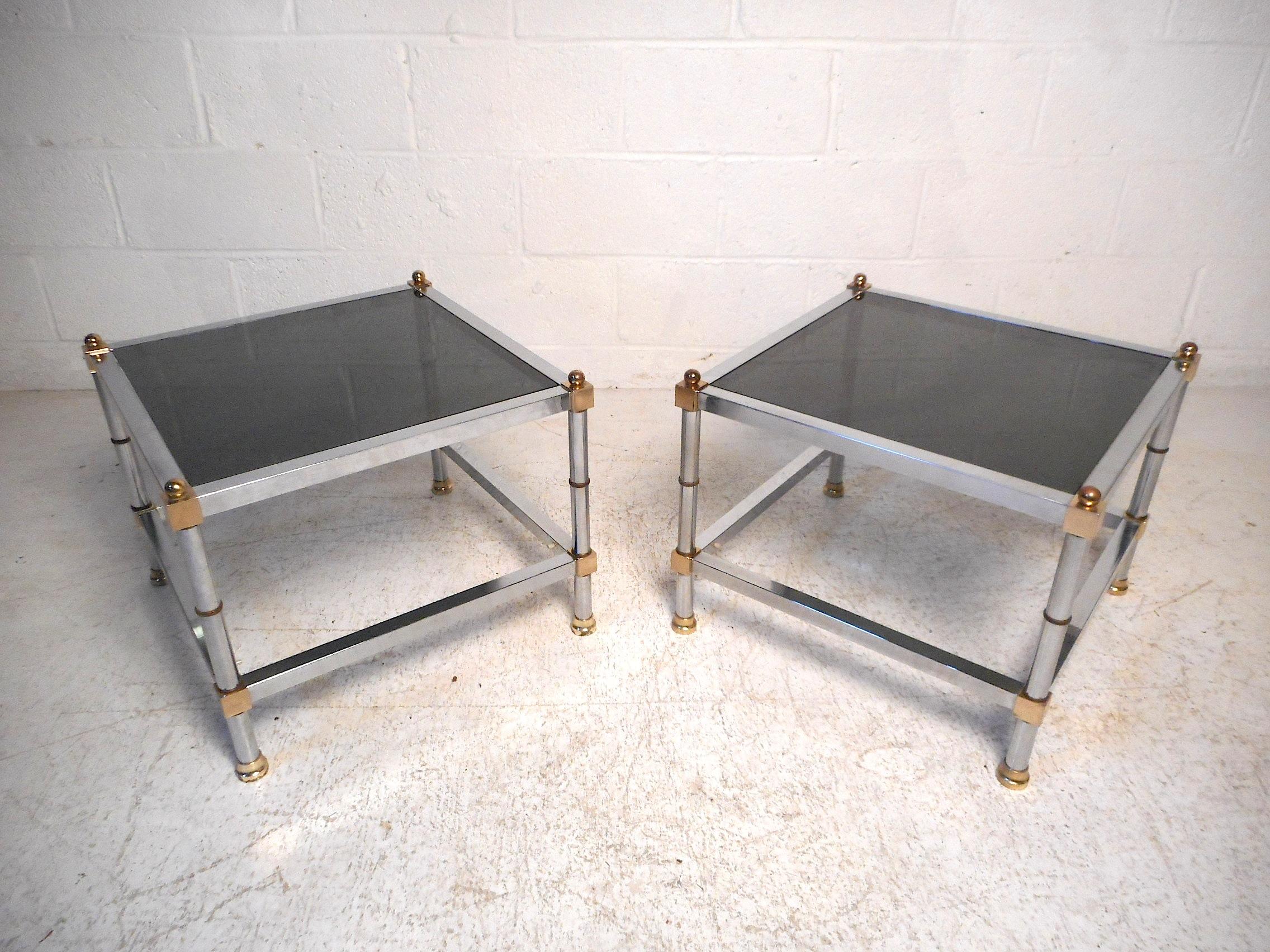 Stylish pair of Regency two-tier side tables. Polished chrome frame with brass accents with smoked glass surfaces. Please confirm item location with dealer (NJ or NY)