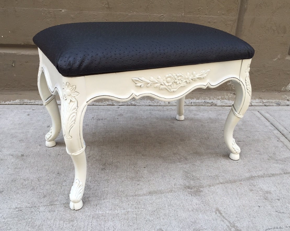 Carved wood frame with a floral pattern. Has a black faux ostrich print upholstered seat.