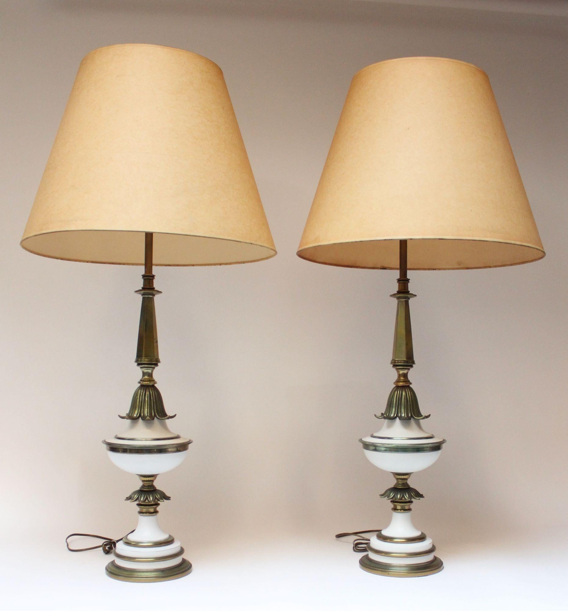 Statuesque Hollywood Regency-Style table lamps by Stiffel composed of solid brass stems and adornments with white enameled metal accents. Includes glass shades/diffusers only (the brown linen shades are for demonstration only and are not