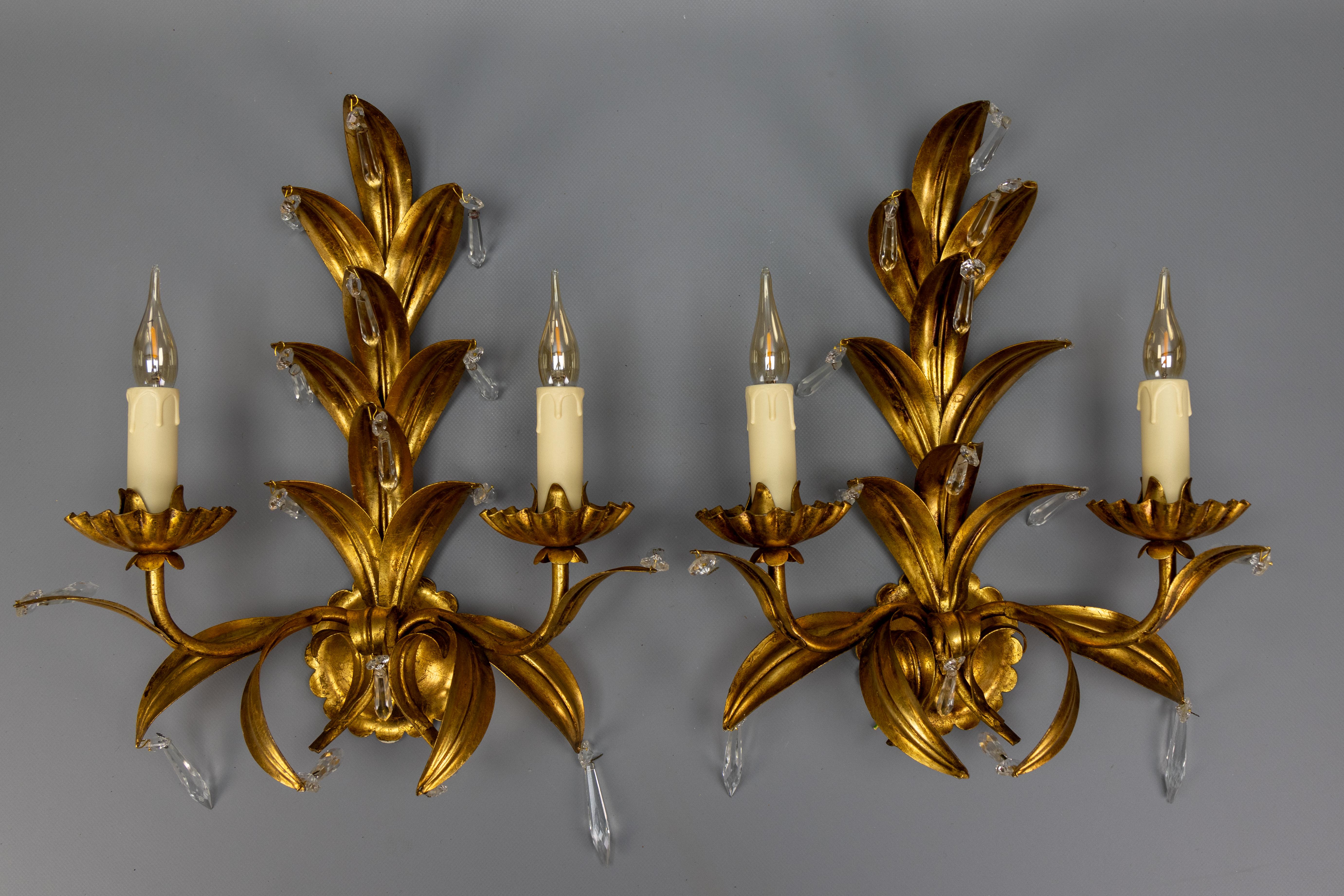 Coppia di applique a due luci in metallo dorato e vetro di cristallo in stile Hollywood Regency, attribuite a Hans Kögl, Germania, circa anni '70.
Questa favolosa coppia di appliques in metallo dorato è caratterizzata da un design a foglia, con