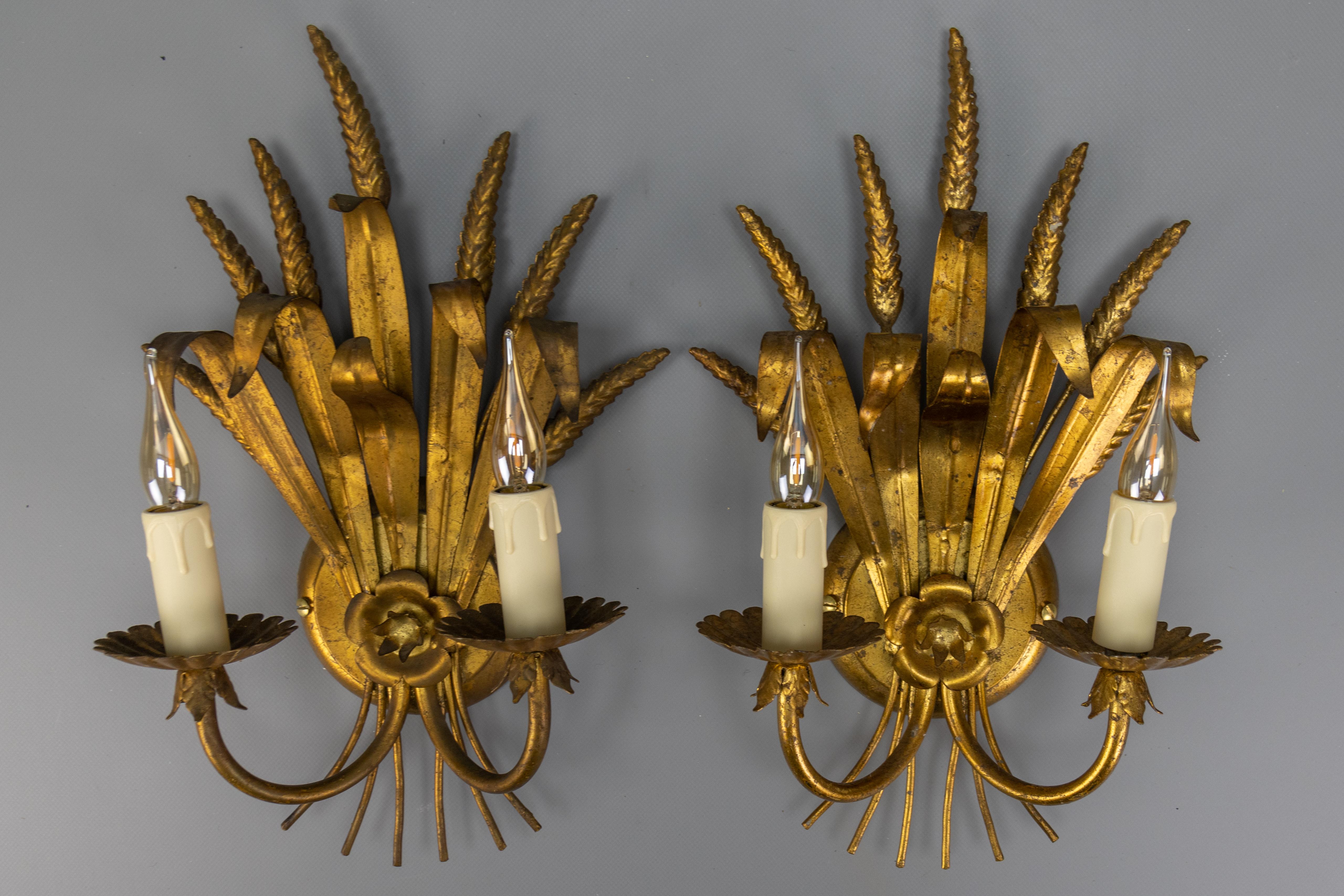 Pair of Hollywood Regency style gilt metal wheat sheaf shaped wall sconces, Germany, circa the 1970s.
This adorable pair of 1970s Hollywood Regency-style double-arm wall sconces features an impressive sheaf of wheat and leaf design crafted in gilded