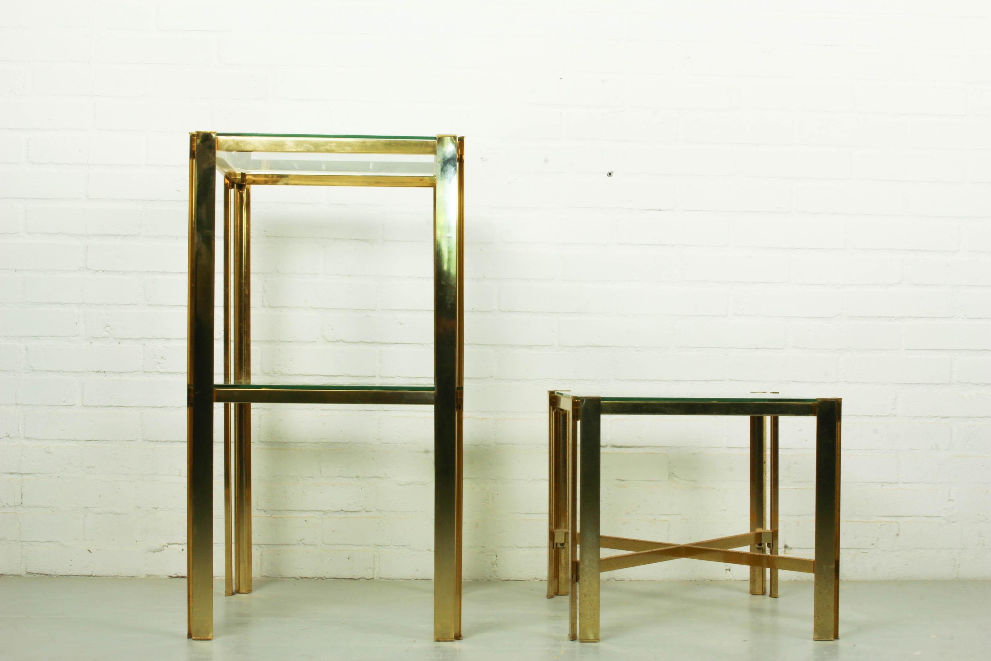 Stylish pair of Hollywood Regency brass and glass side tables. Brass frame with glass surfaces.

Dimensions low table: 41 cm W, 41cm D, 36cm H.
Dimensions high table: 41cm W, 41cm D, 74cm H.