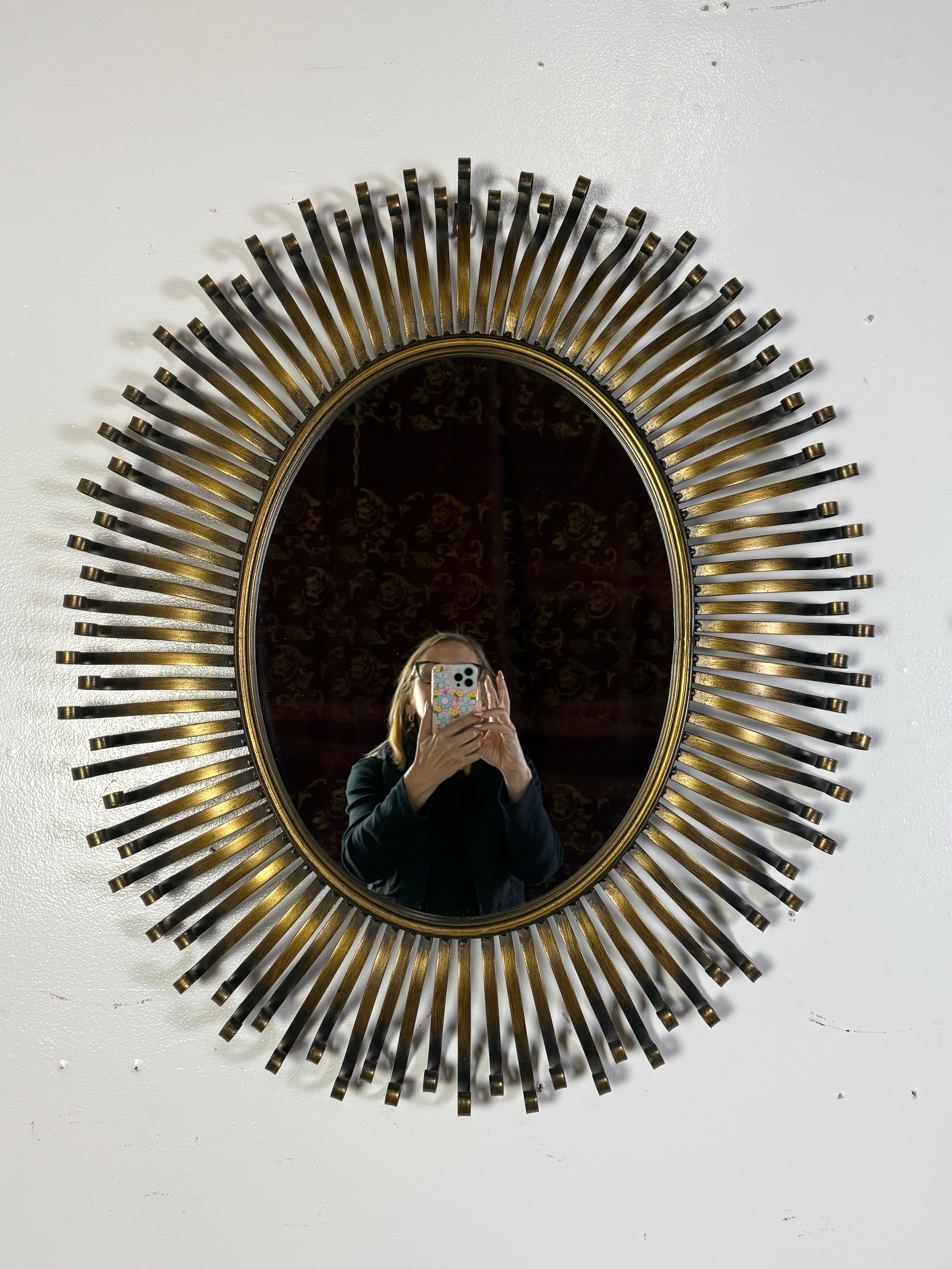 This is a stunning pair of vintage brass sunburst mirrors, distinguished by their bold, sculptural design and elegant patina. Each mirror features an oval center mirror encased in a brass frame, surrounded by a dynamic burst of individually curved