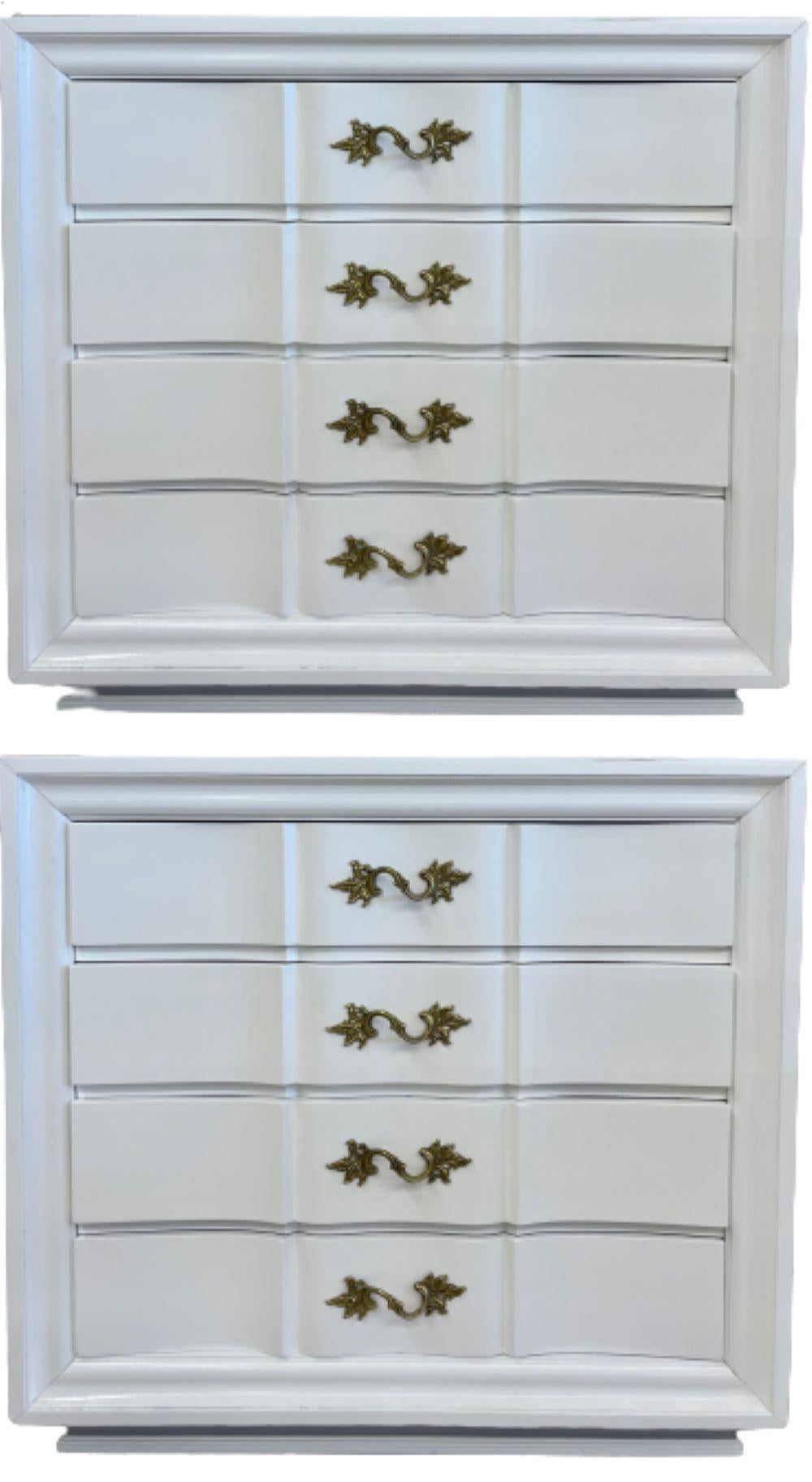 A pair of Hollywood Regency style white lacquered dressers or commode or chest. Each of these multiple use chests or nightstands have been recently refinished. The pair have solid bronze pulls on all four double curved front drawers sitting on a