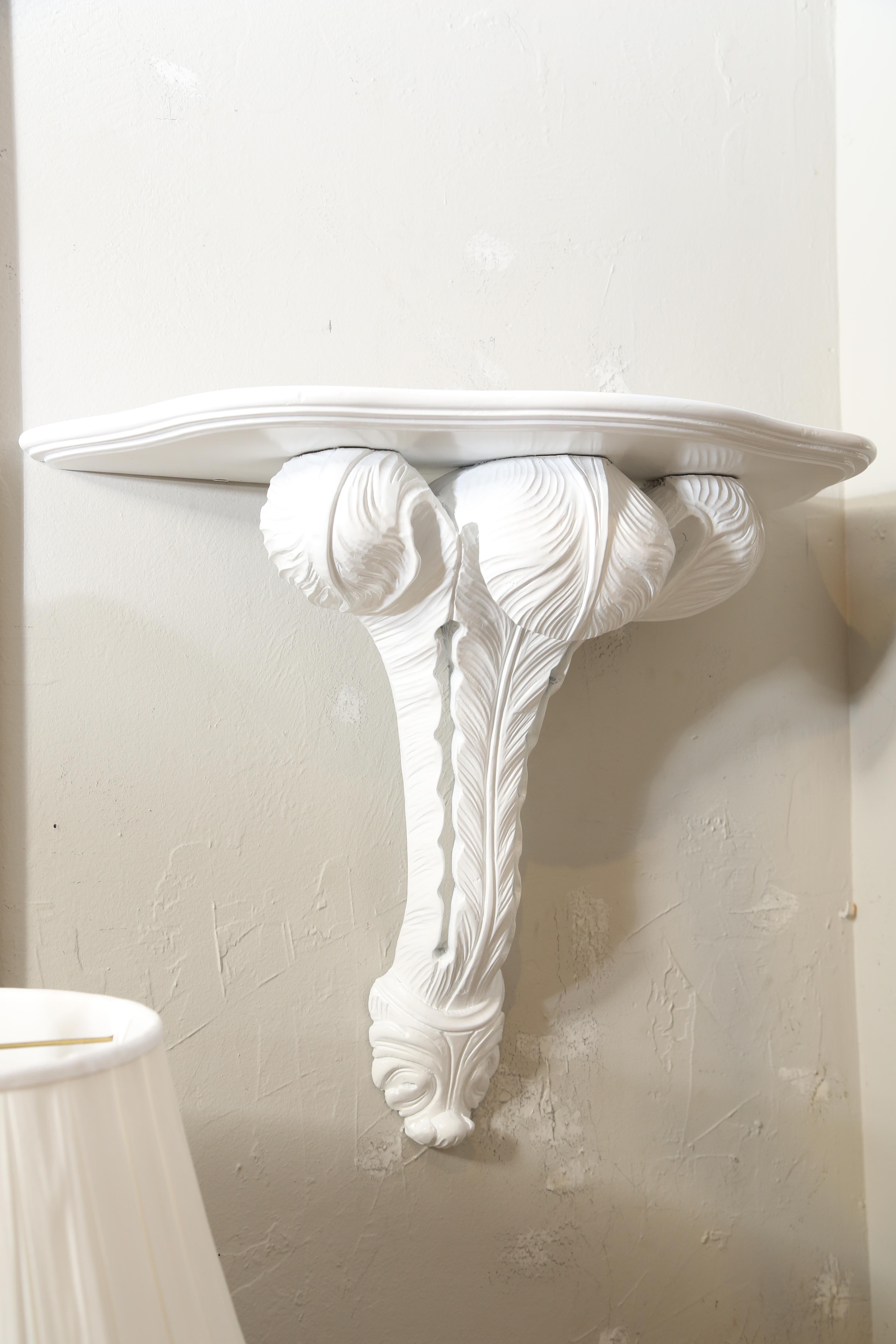Large pair of carved and white lacquered wall brackets in the Hollywood Regency style.