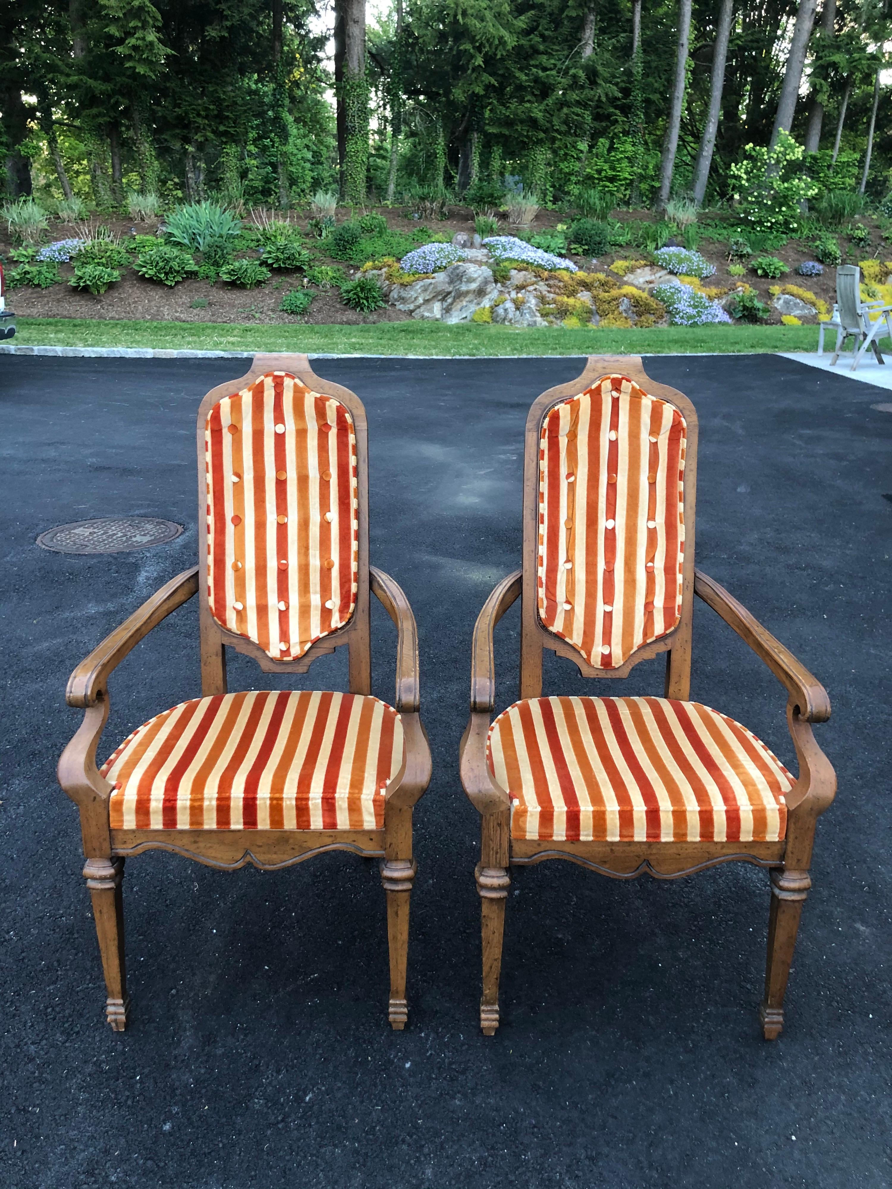 Pair of Hollywood Regency velvet arm chairs by Heritage . Whimsical pinstripe design with a two tone gold and a raspberry color velvet. The velvet covers the fully caned back and the fabric has little buttons that come thru the caning on the reverse