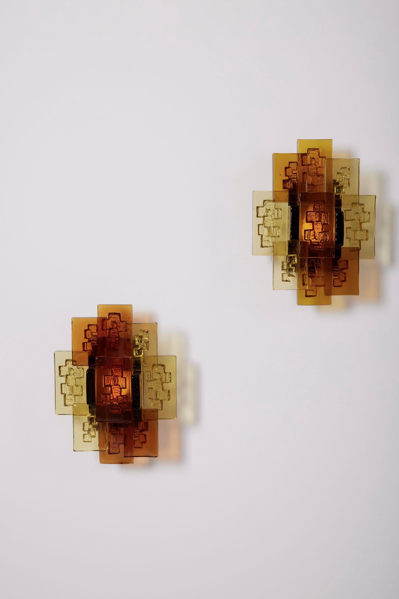 Paire d'appliques en verre du designer danois Svend Aage Holm Sørensen (1913-2004), datant des années 1950. Le diffuseur est composé d'un ensemble de rectangles épais en verre ambré et jaune. En très bon état général.

LP1965