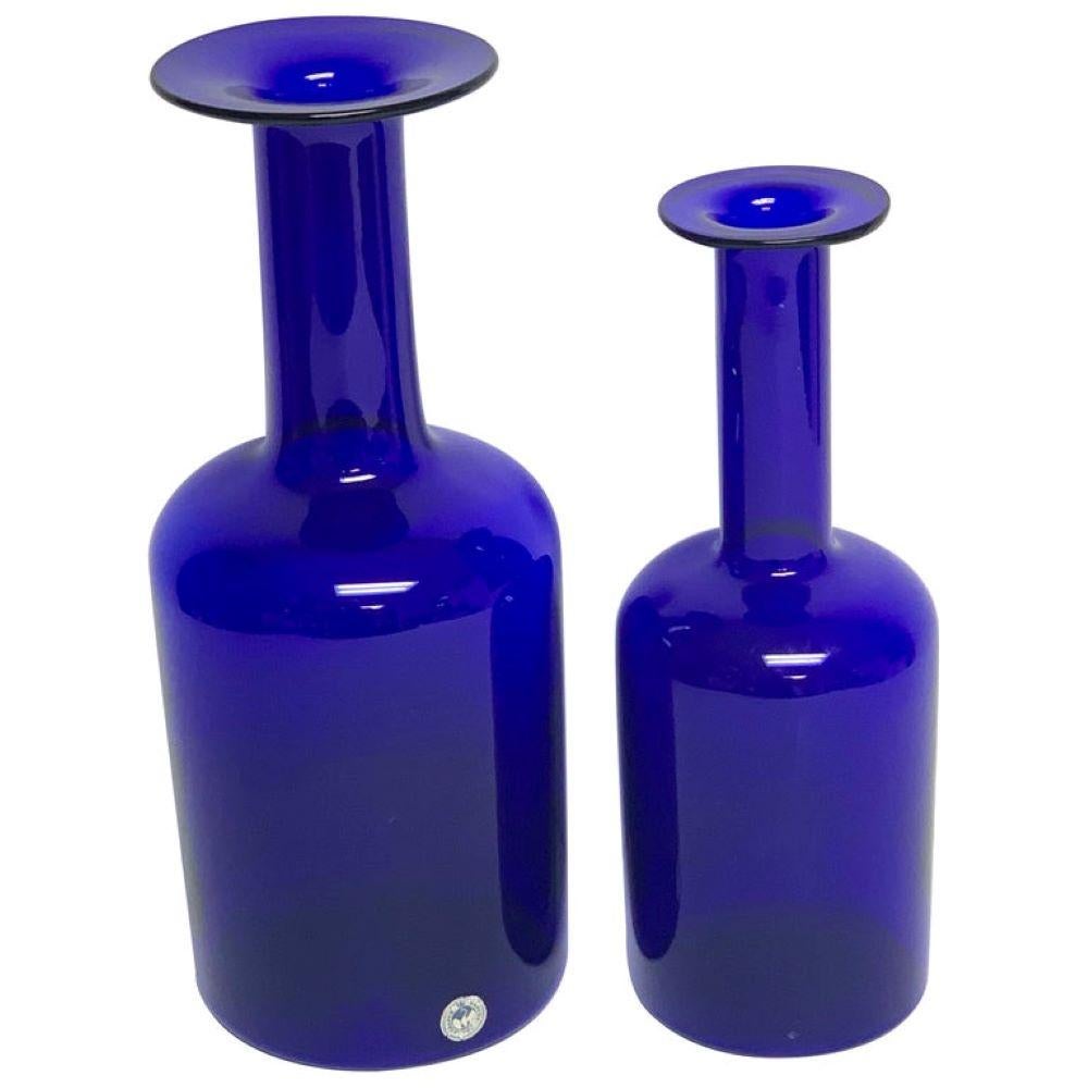 A Pair of Holmegaard Gulv Vases by Otto Bauer in Blue
Denmark, 1960s

Pair of graduating Holmegaard blue glass'Gulv' vases, by Otto Bauer Each one of the iconic bottles has a wide rim, an elongated neck, and a wide, round base. 

Measurements of the