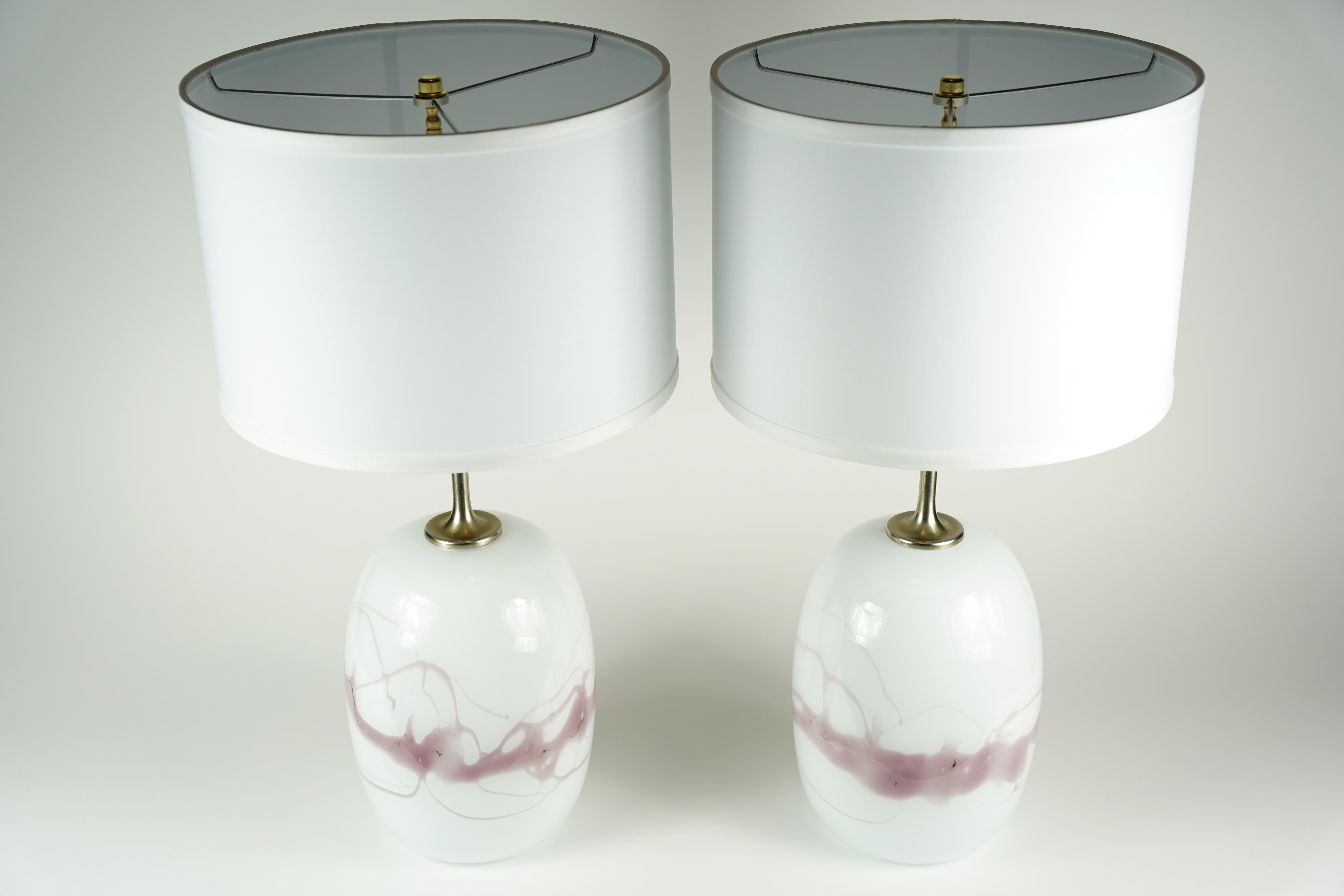 Zwei Holmegaard-Lampen mit gebürsteten Stahlbeschlägen von Holmegaard, Dänemark 1984. Weiße Glassockel mit einer Vielzahl von rot gefärbten Glasschmelzen unter dem glatten Klarglas, entworfen von Michael Bang, 1984.
Die Höhe von 14