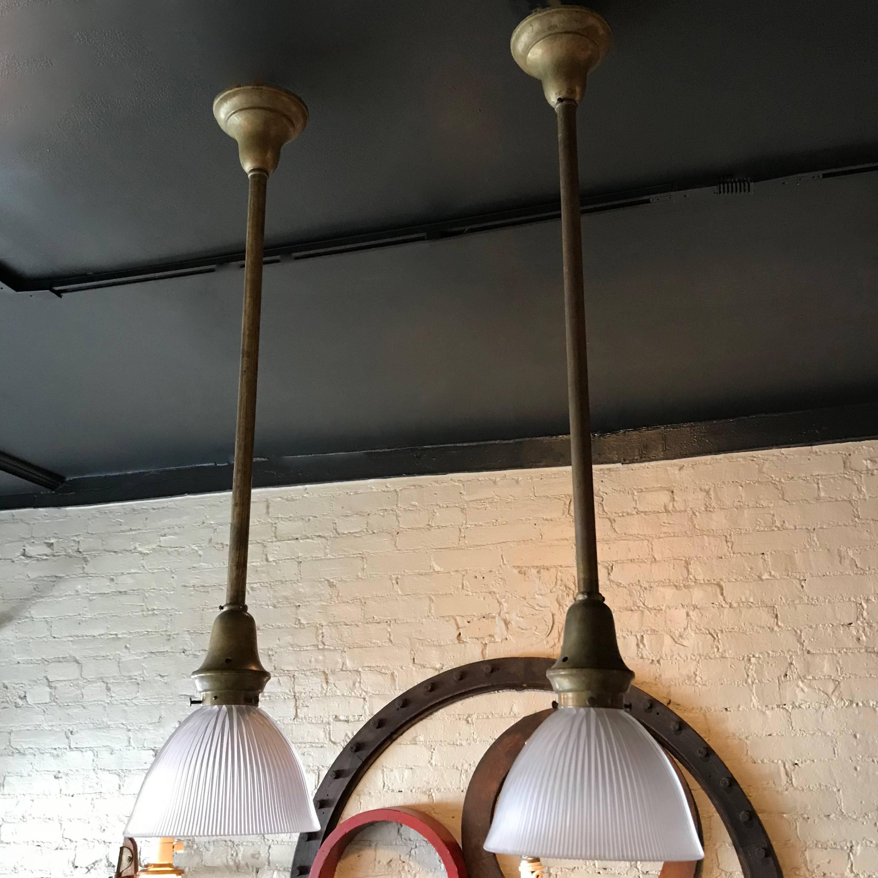Early 20th century, industrial, factory pendant light feature deeply cut, prismatic Holophane dome shade with brass fitter on brass pole with matching canopy. The lamp is newly wired to accept a 200 watt bulb. The shade height is 5 inches. One