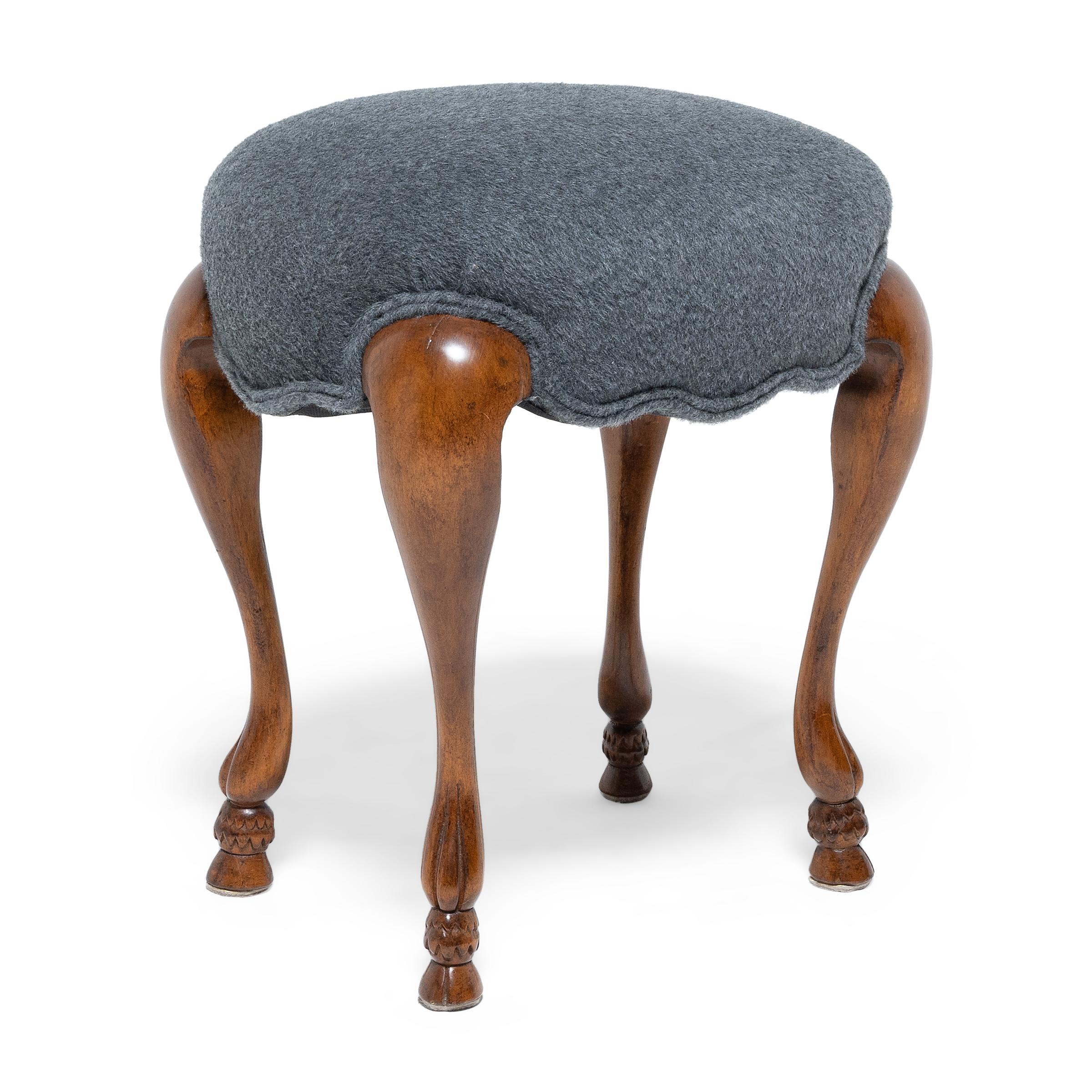 This pair of low upholstered stools are designed in the style of 18th century French furniture, taking cues from the feminine forms and curved lines of Louis XV-style seating. The padded oval seats are upholstered in rich grey alpaca wool. Each