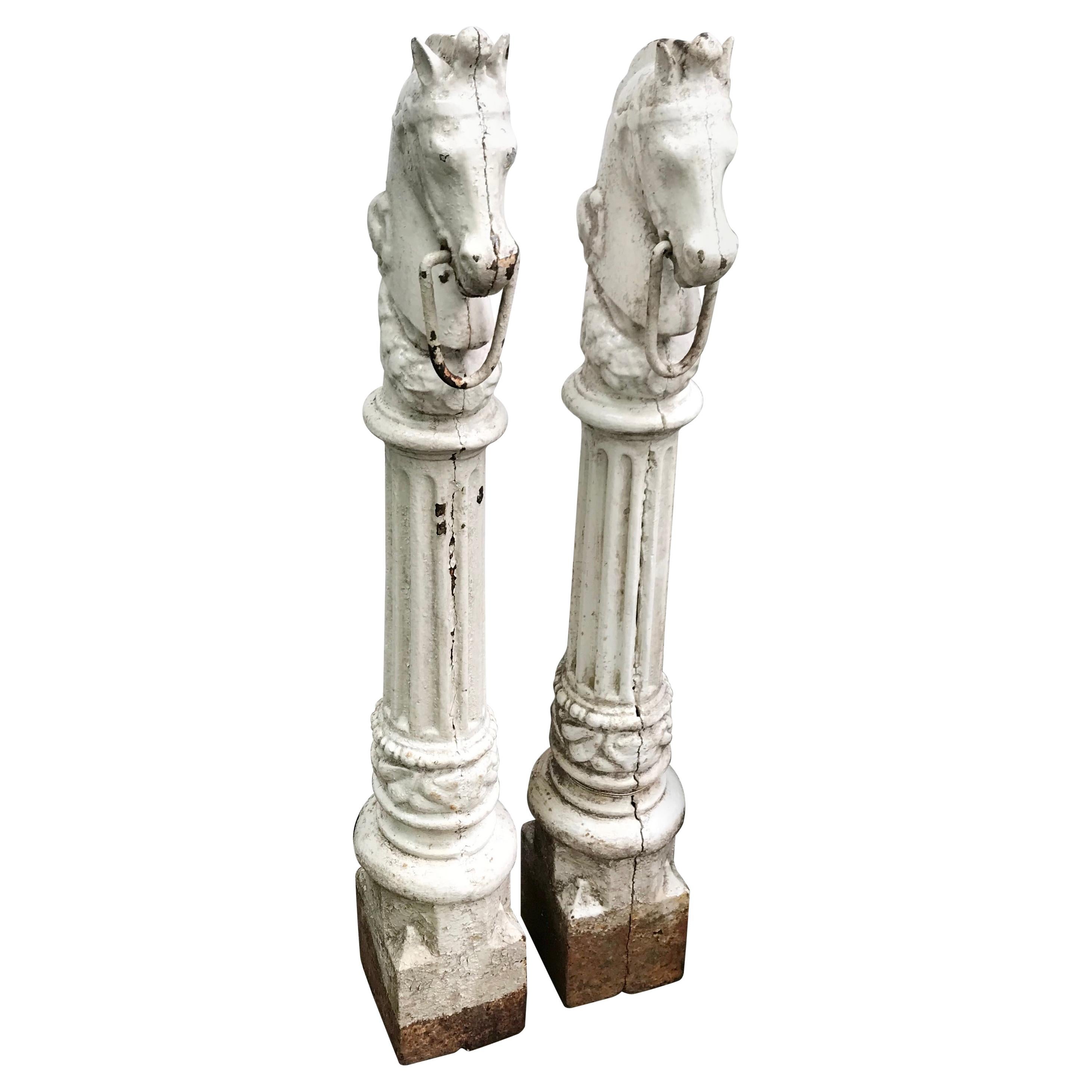 Pair of horse head hitching posts. Superb pair antique painted cast iron hitching posts with horse heads with moveable horse bits on garlanded fluted columnar shafts on modeled plinth bases. Original painted condition with some areas of later