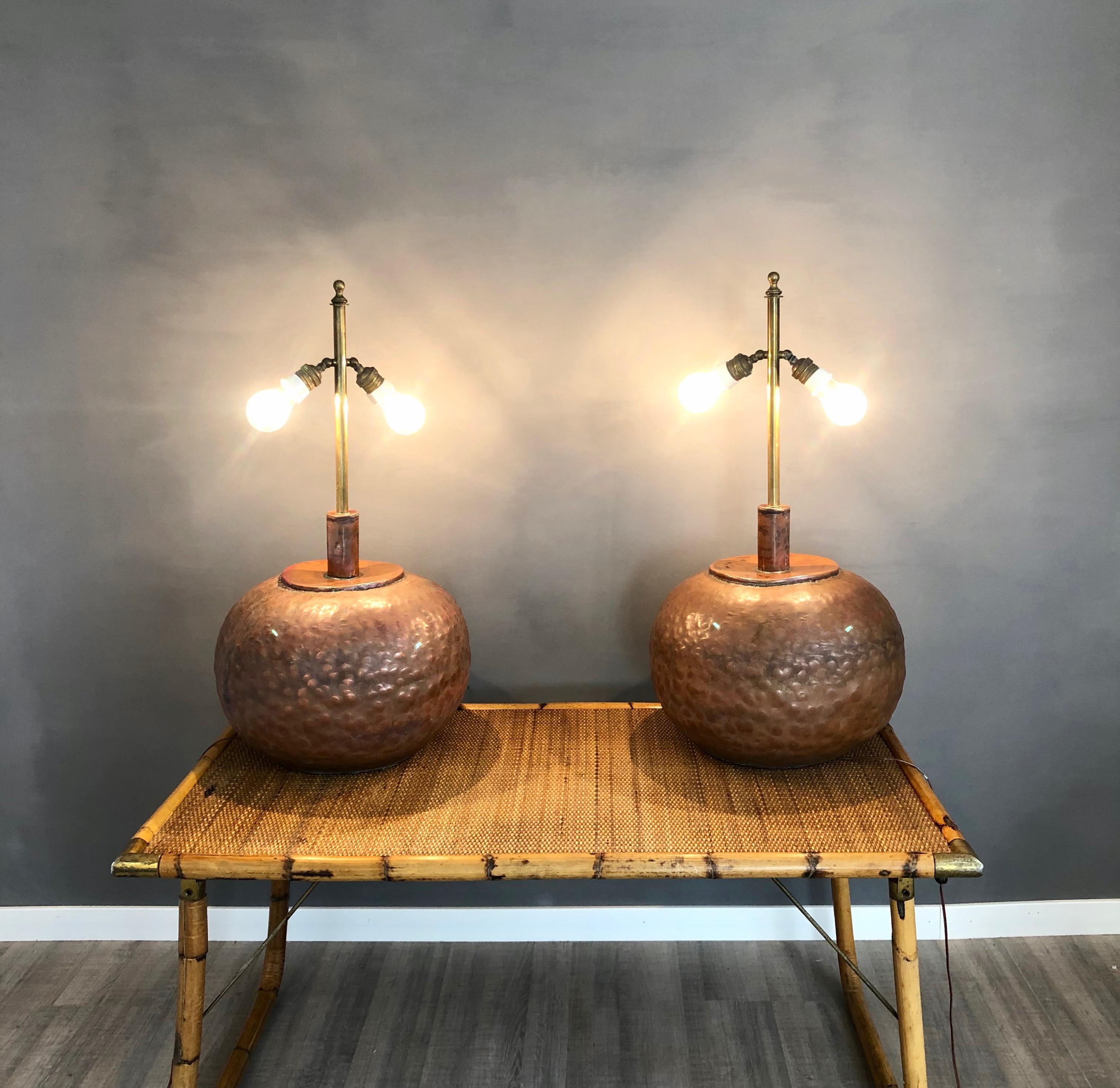 These huge table lamps are made in copper and presents a circular shape with a brass stick from which depart two adjustable light bulbs. They are sold without the lampshade, but the customer can put on them any lampshade he/she likes. Made in
