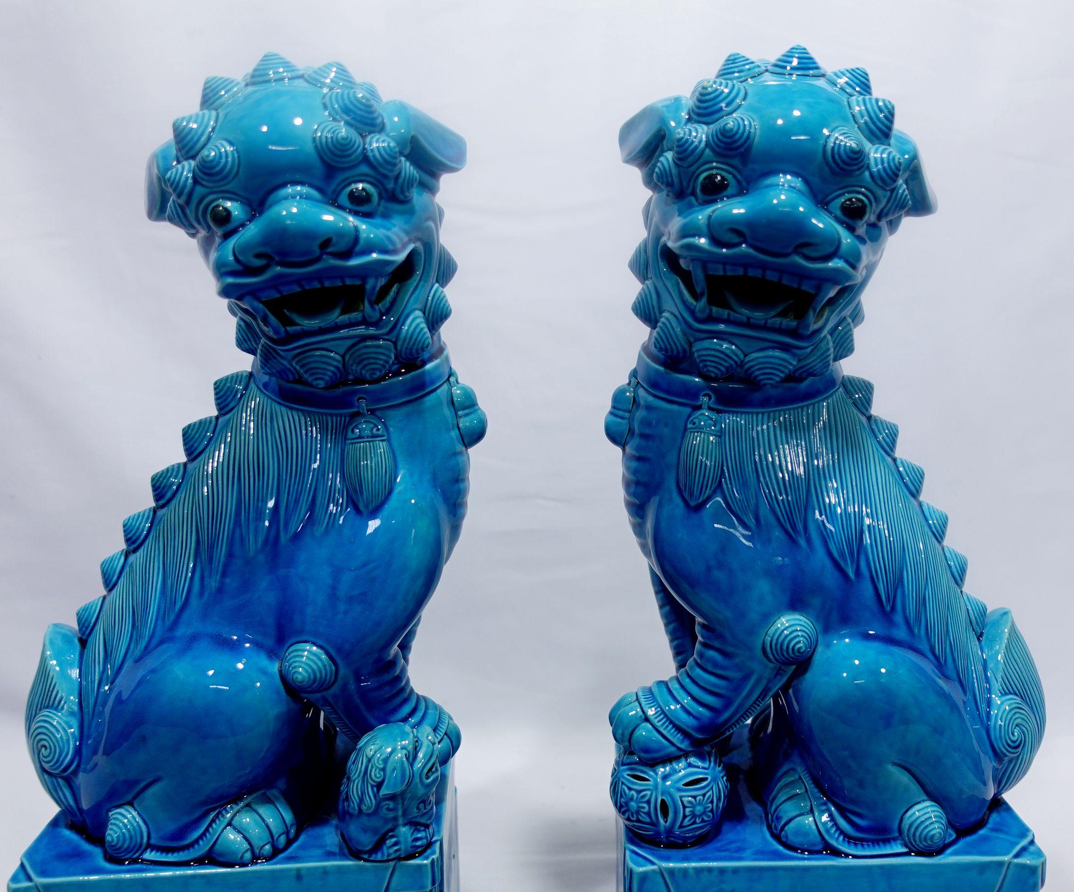 Huge, Fine, and very detailed pair of Chinese turquoise glazed foo dogs from the mid-20th century. The hollow biscuit porcelain figures stand raised on a rectangular base and look sideways with open mouths and tongues showing teeth each with a